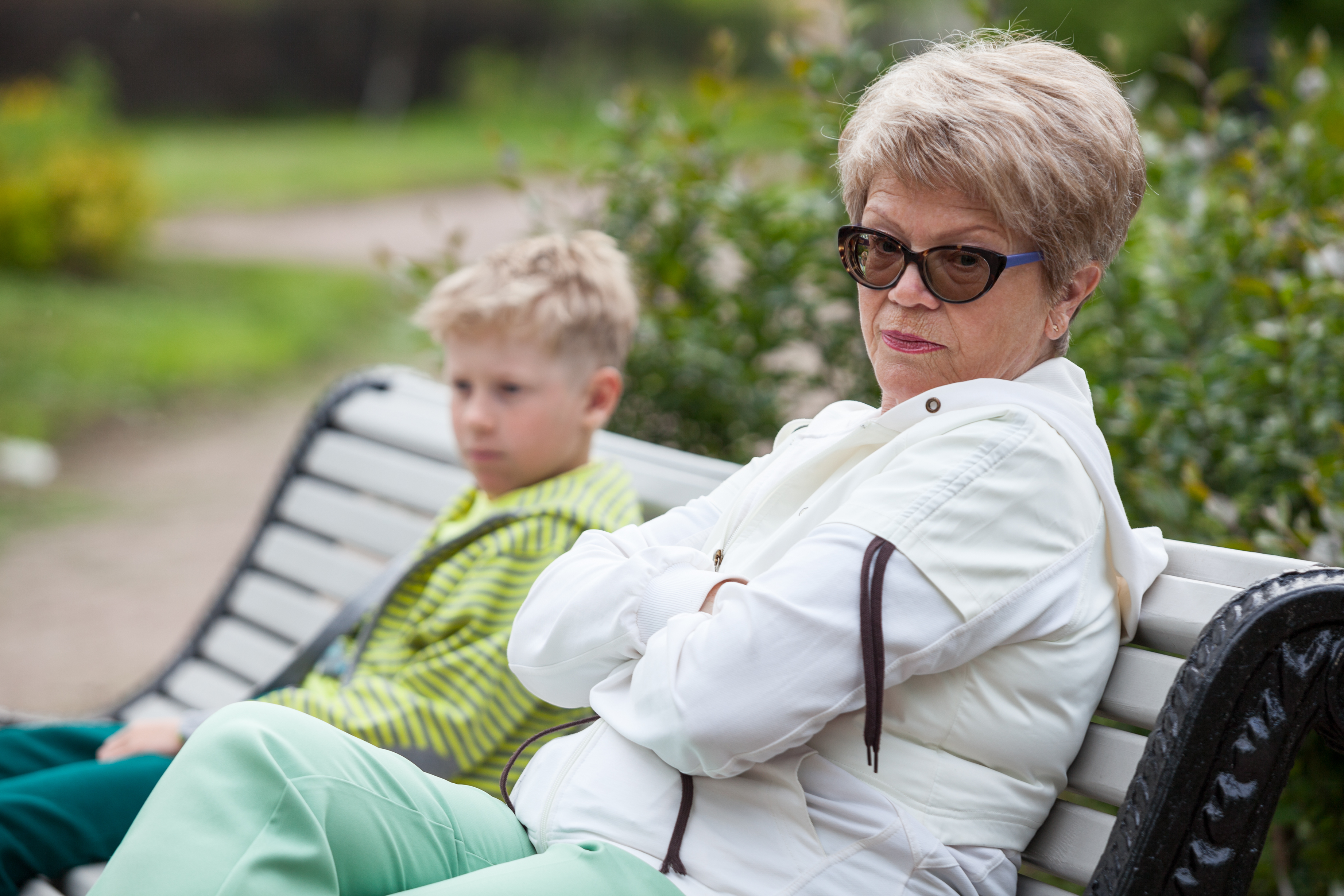 Mujer mayor ignorando a un chico joven en un banco | Fuente: Shutterstock