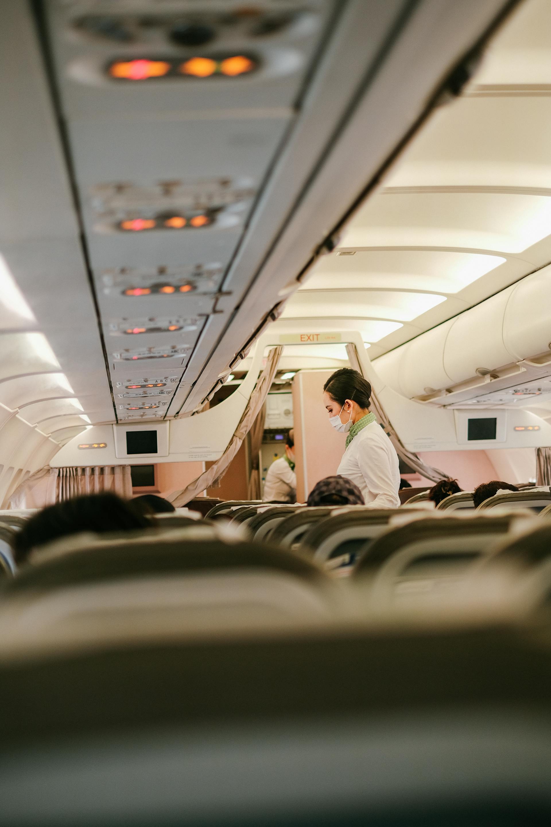 Una azafata de pie cerca de la gente sentada en los asientos del avión | Fuente: Pexels