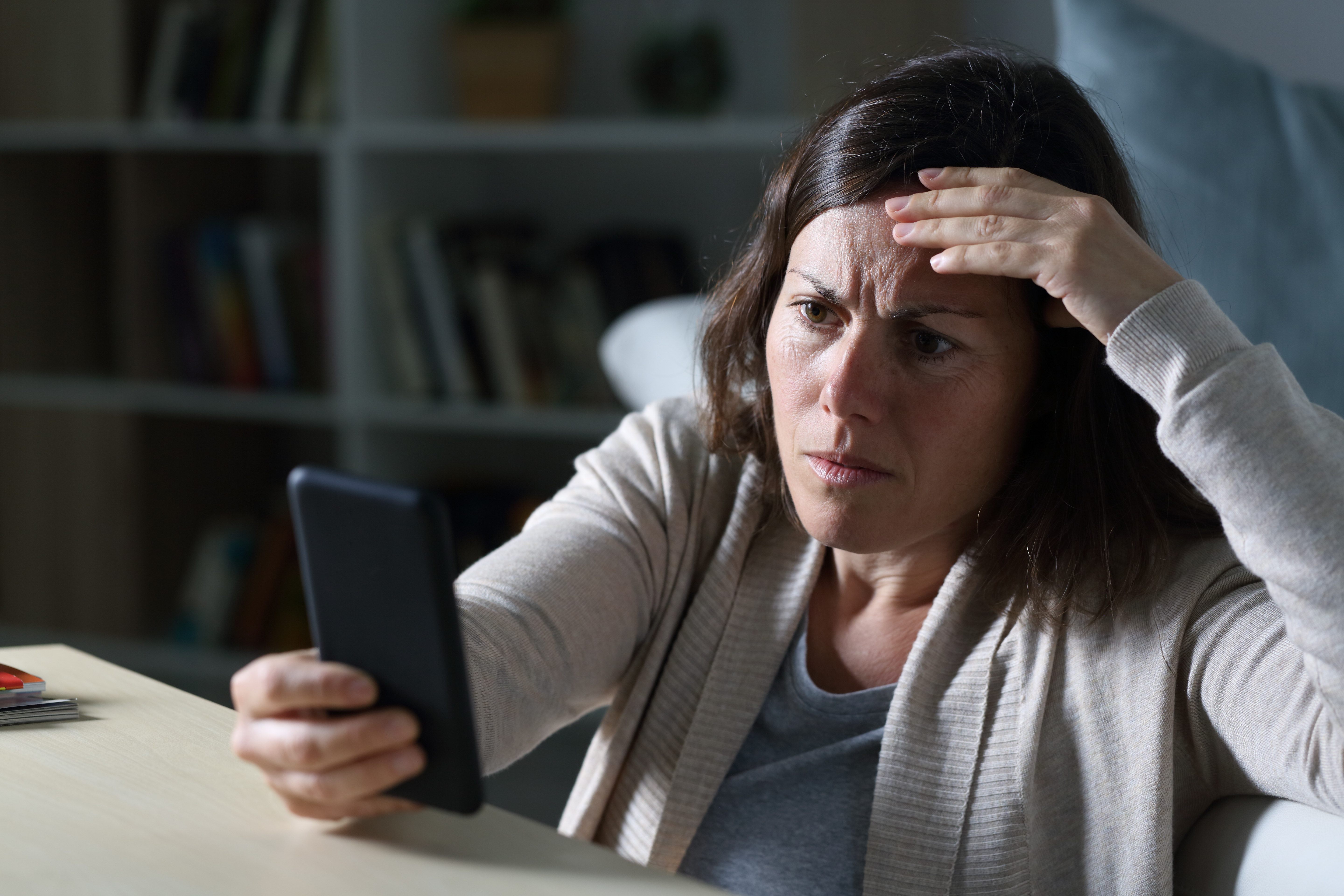 Una mujer con cara de preocupación mientras mira un teléfono | Foto: Shutterstock