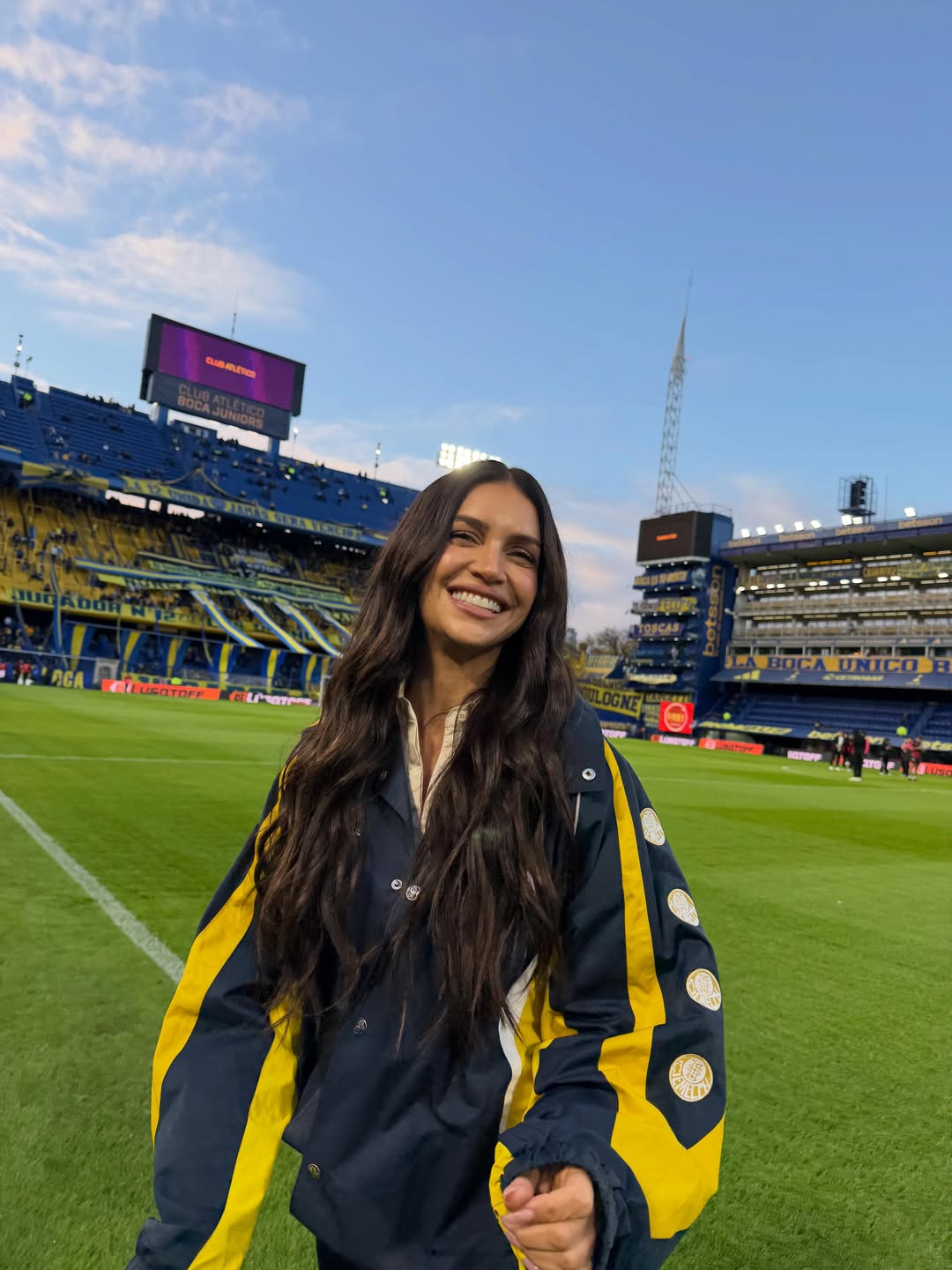 Zaira Nara sonríe sobre el césped de La Bombonera durante su visita al estadio de Boca Juniors con una campera azul y amarilla del club. | Fuente: Instagram/zaira.nara