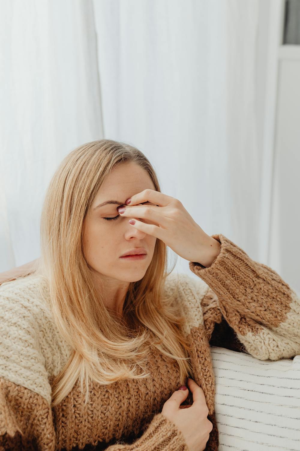 Una mujer ceñuda frotándose las cejas ⏐ Fuente: Pexels