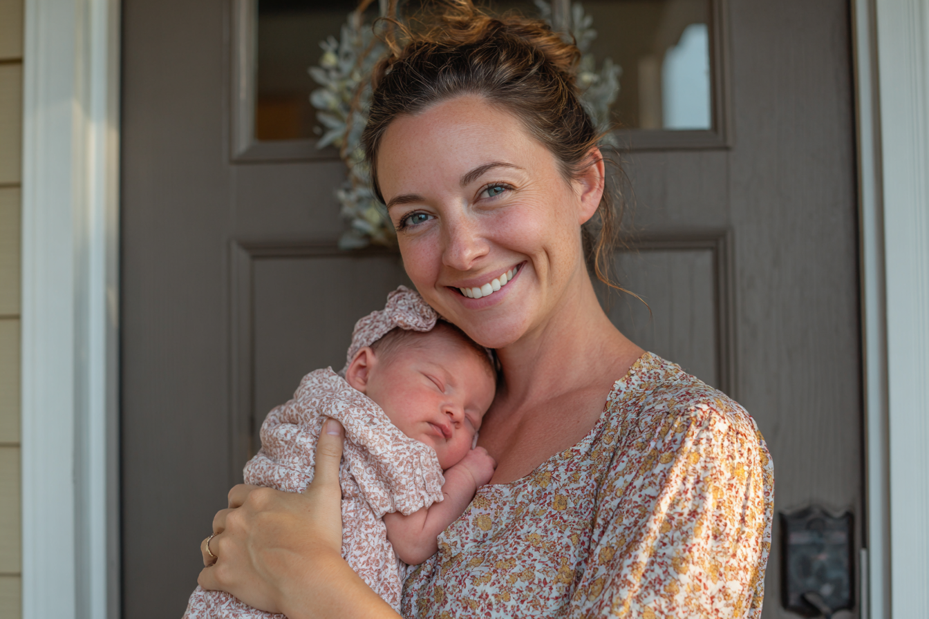 Una mujer sonriente con su hija recién nacida en brazos | Fuente: Midjourney