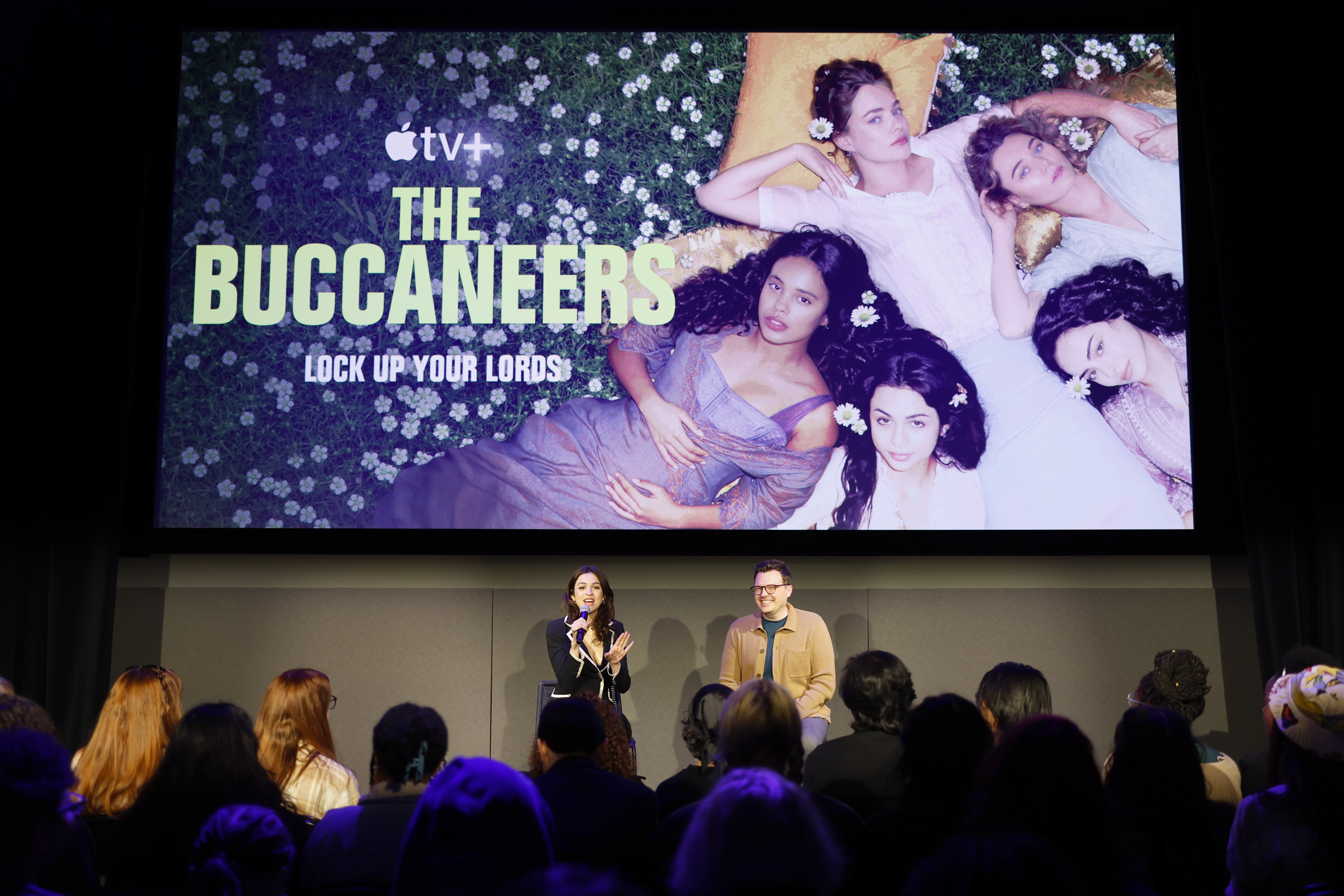 Josie Totah interviene durante la mesa redonda sobre "The Buccaneers" en la segunda jornada del 12º SCAD TVfest, sentada en el escenario junto a otro participante mientras se dirigen al público. En la pantalla que tienen detrás se ve una gran imagen promocional de la serie de Apple TV+. | Fuente: Getty Images