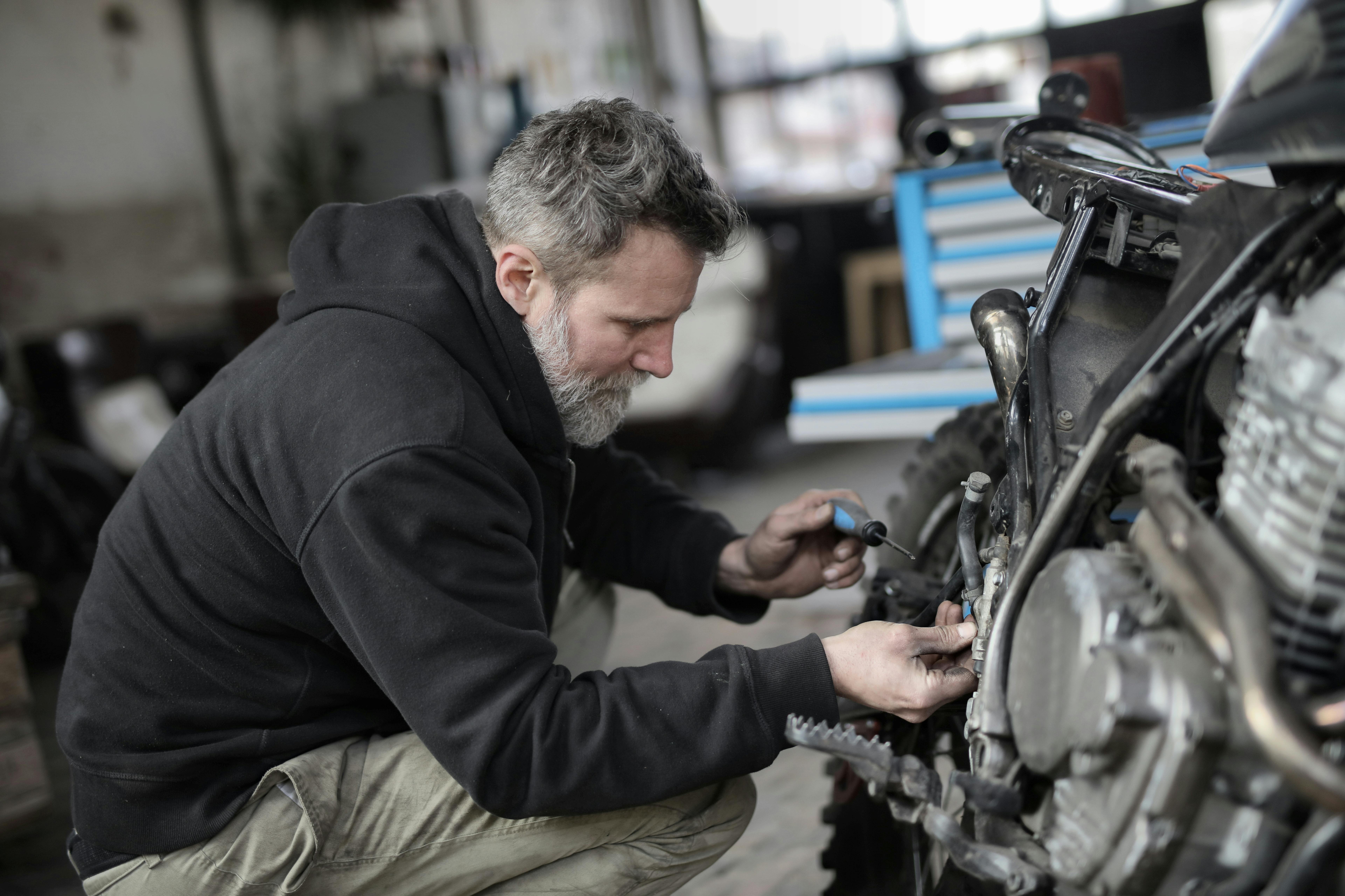 Un hombre mayor trabajando en una bicicleta | Fuente: Pexels