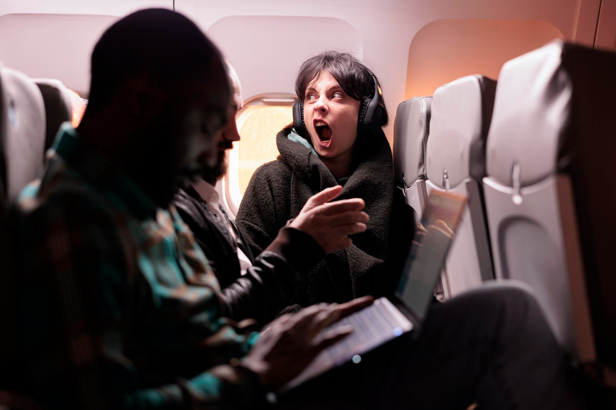 Mujer alterada con auriculares mientras grita en un vuelo | Fuente: Freepik