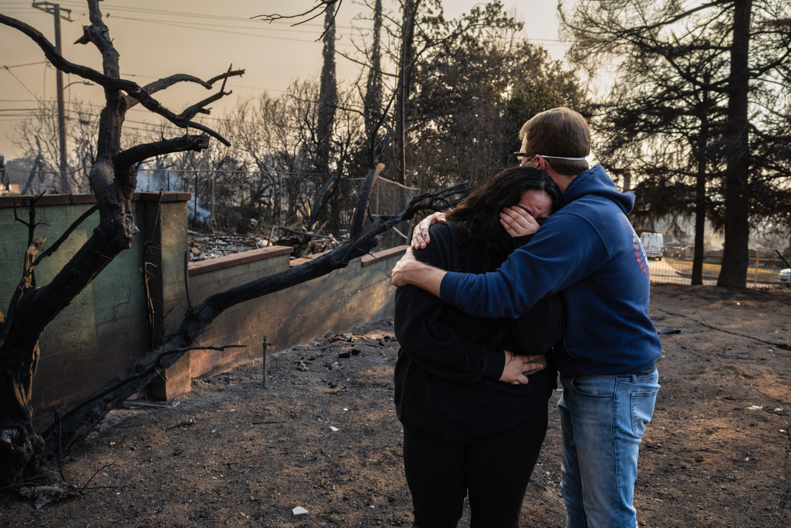 Un hombre abraza a su hija sobre las ruinas carbonizadas de su casa familiar quemada en el Incendio Eaton el 9 de enero de 2025, en Altadena, California. | Fuente: Getty Images