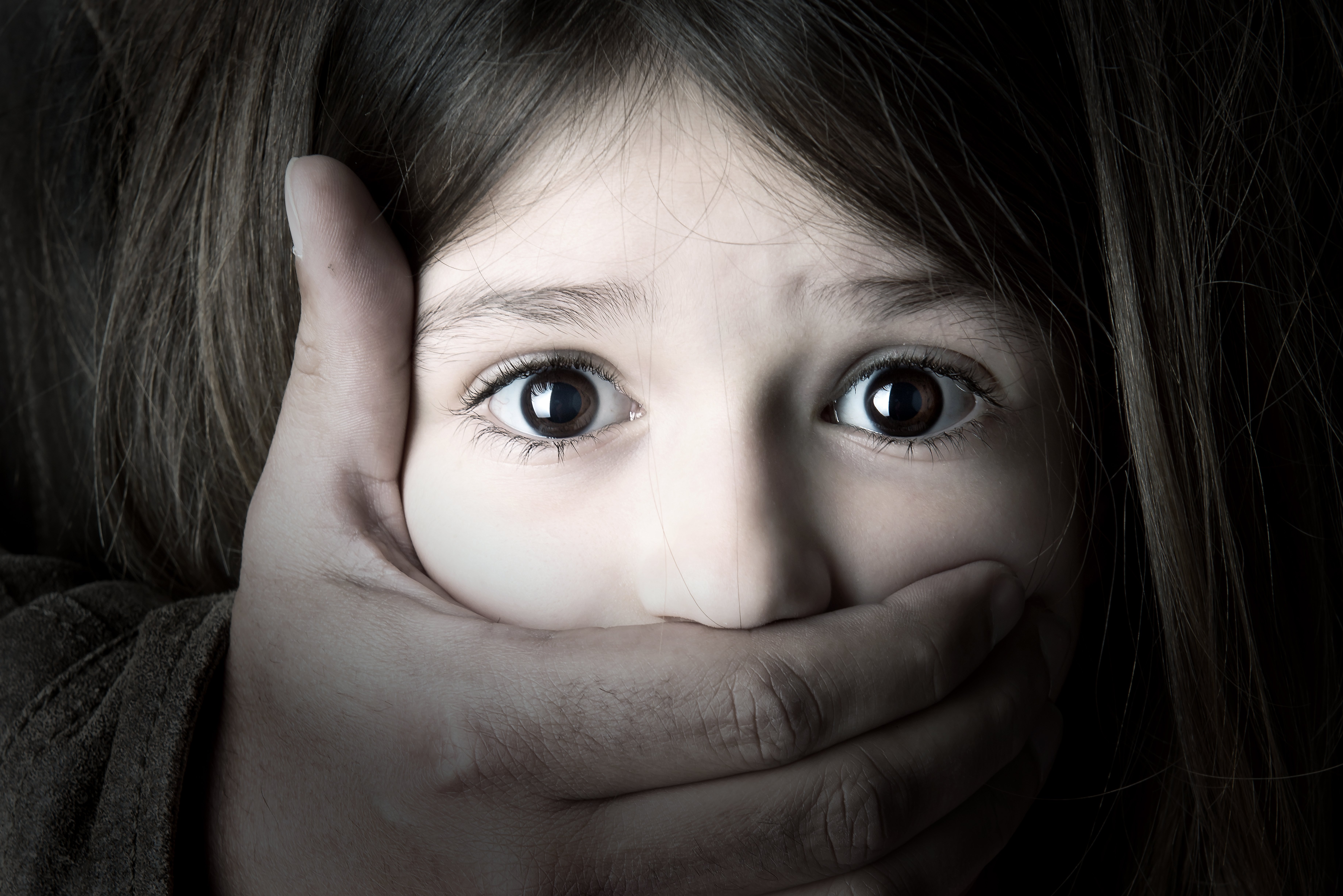 A una niña le tapan la boca con una mano. Fuente: Shutterstock