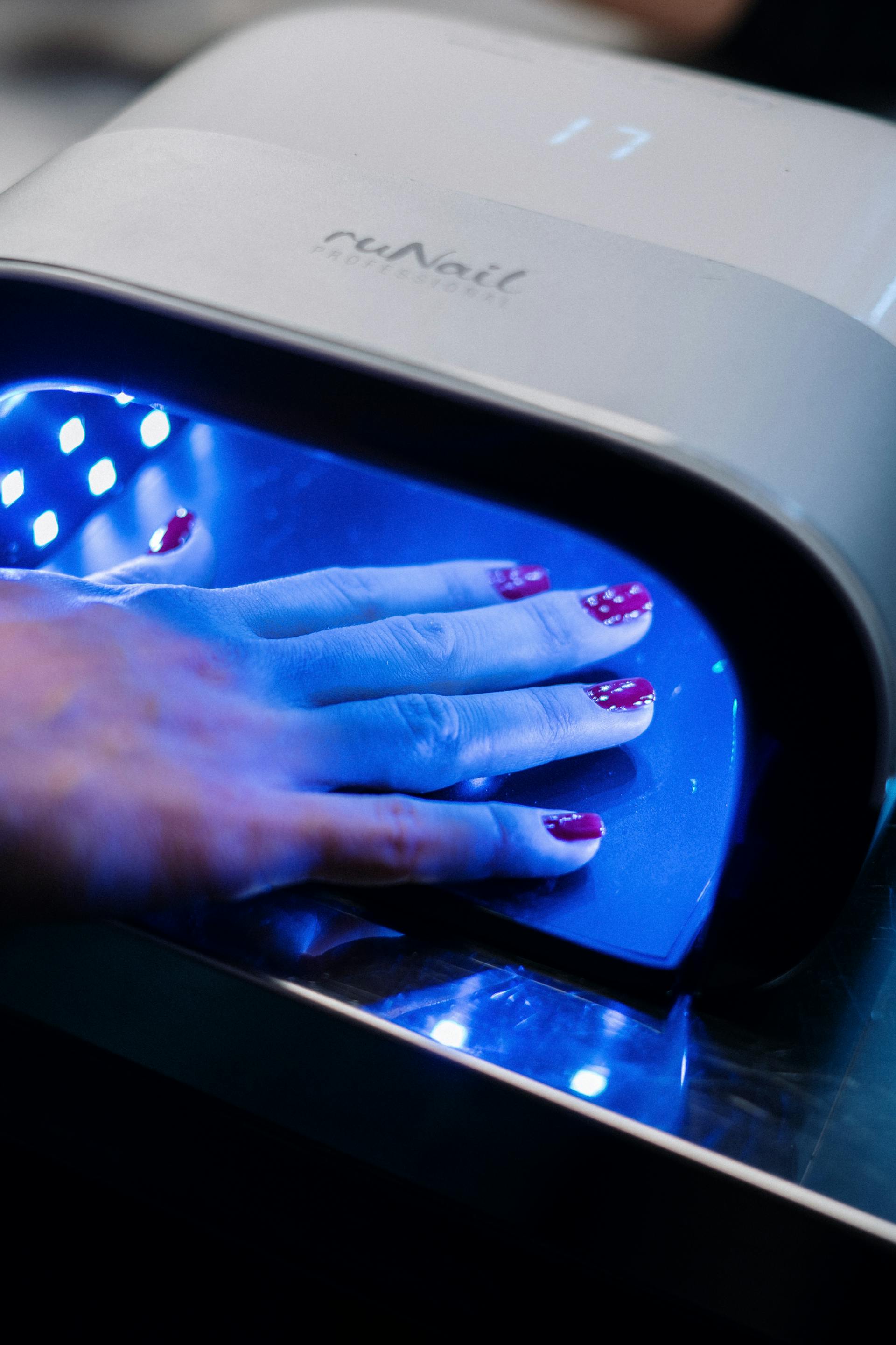 Una mano en una máquina de uñas UV | Foto: Pexels