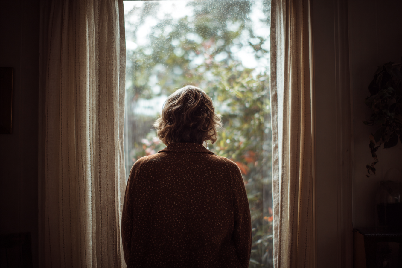 Una donna che guarda fuori da una finestra | Fonte: Midjourney