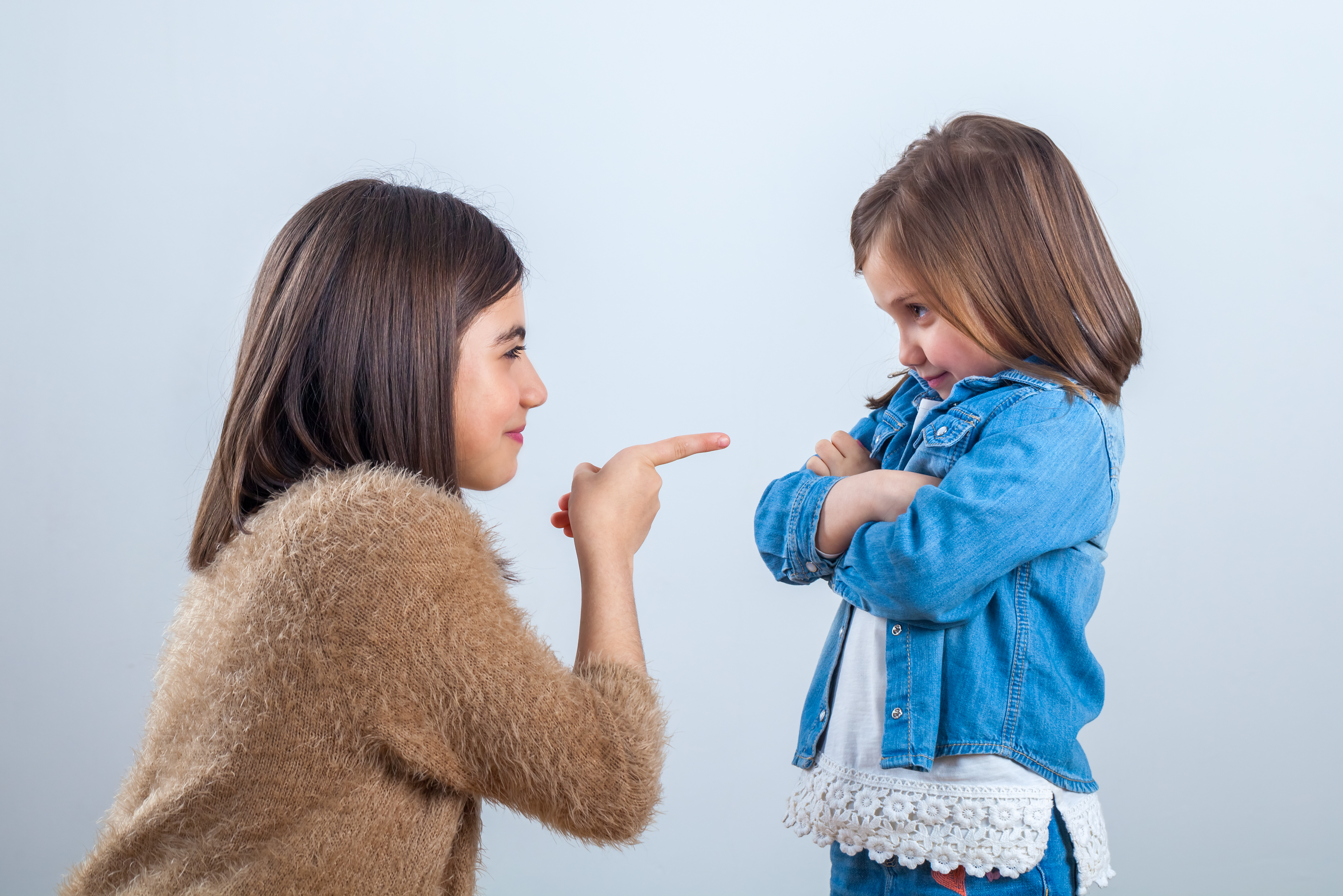 La hermana mayor hace un comentario a la pequeña con un dedo | Foto: Getty Images