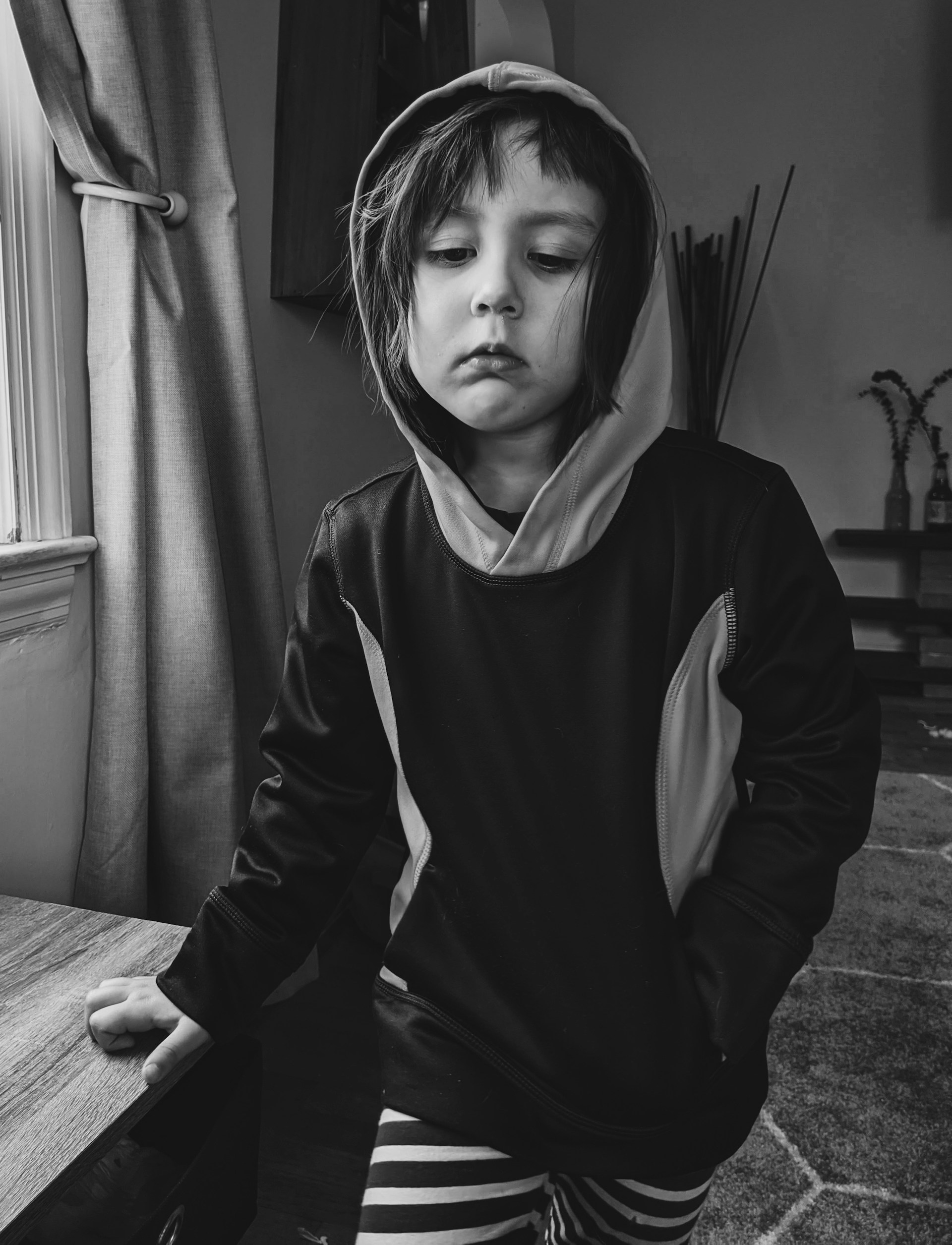 Foto in scala di grigi di un bambino assorto | Fonte: Unsplash