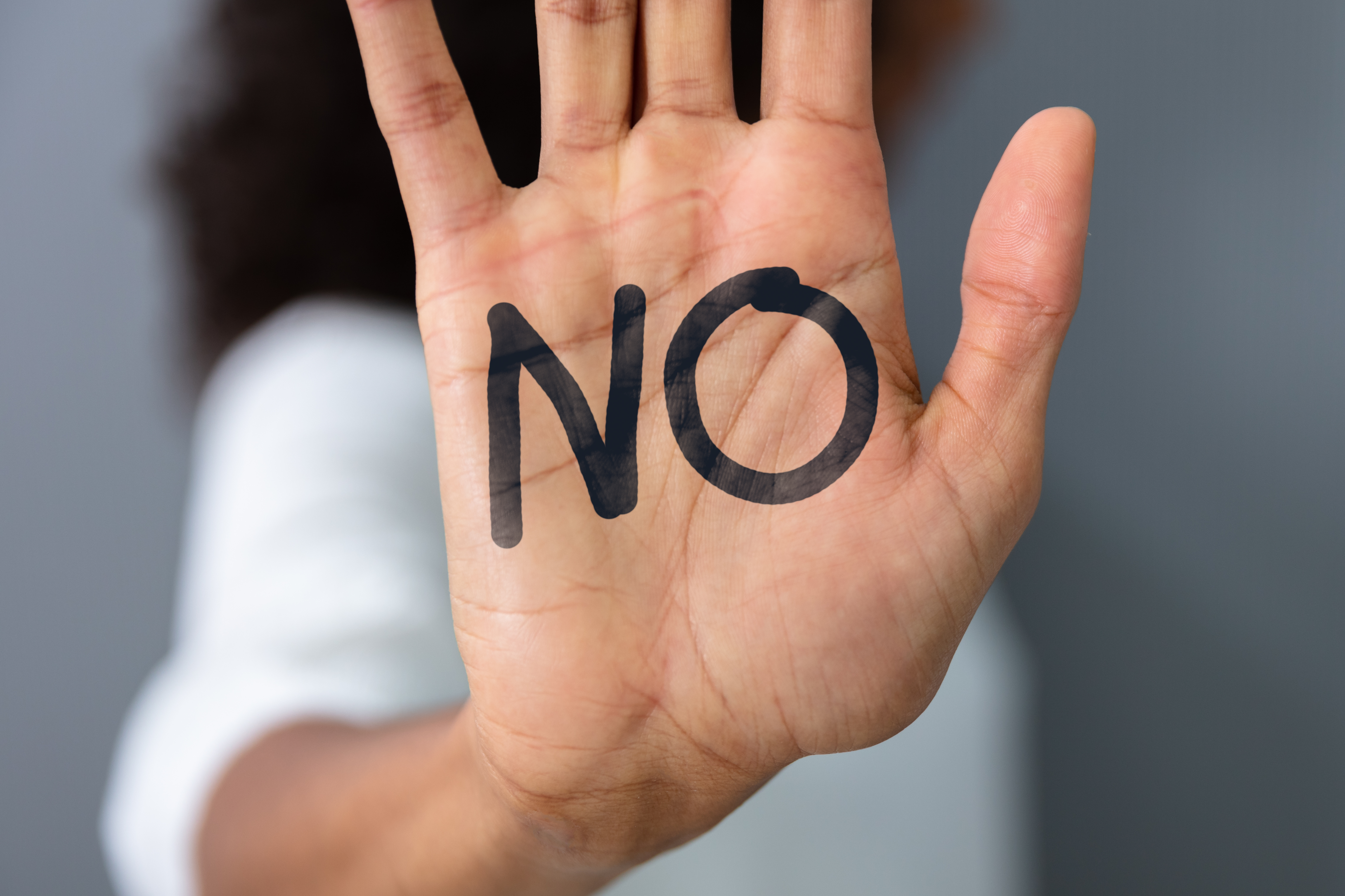 La mano levantada de una mujer con el texto "No" | Foto: Shutterstock