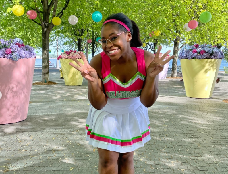 Carla Jeffery sonríe a la cámara con su característico uniforme de animadora de Seabrook, reflejando el espíritu alegre y divertido que aportó a su papel de Bree en la serie "Zombies" de Disney Channel. | Fuente: Instagram/chandlerlkinney