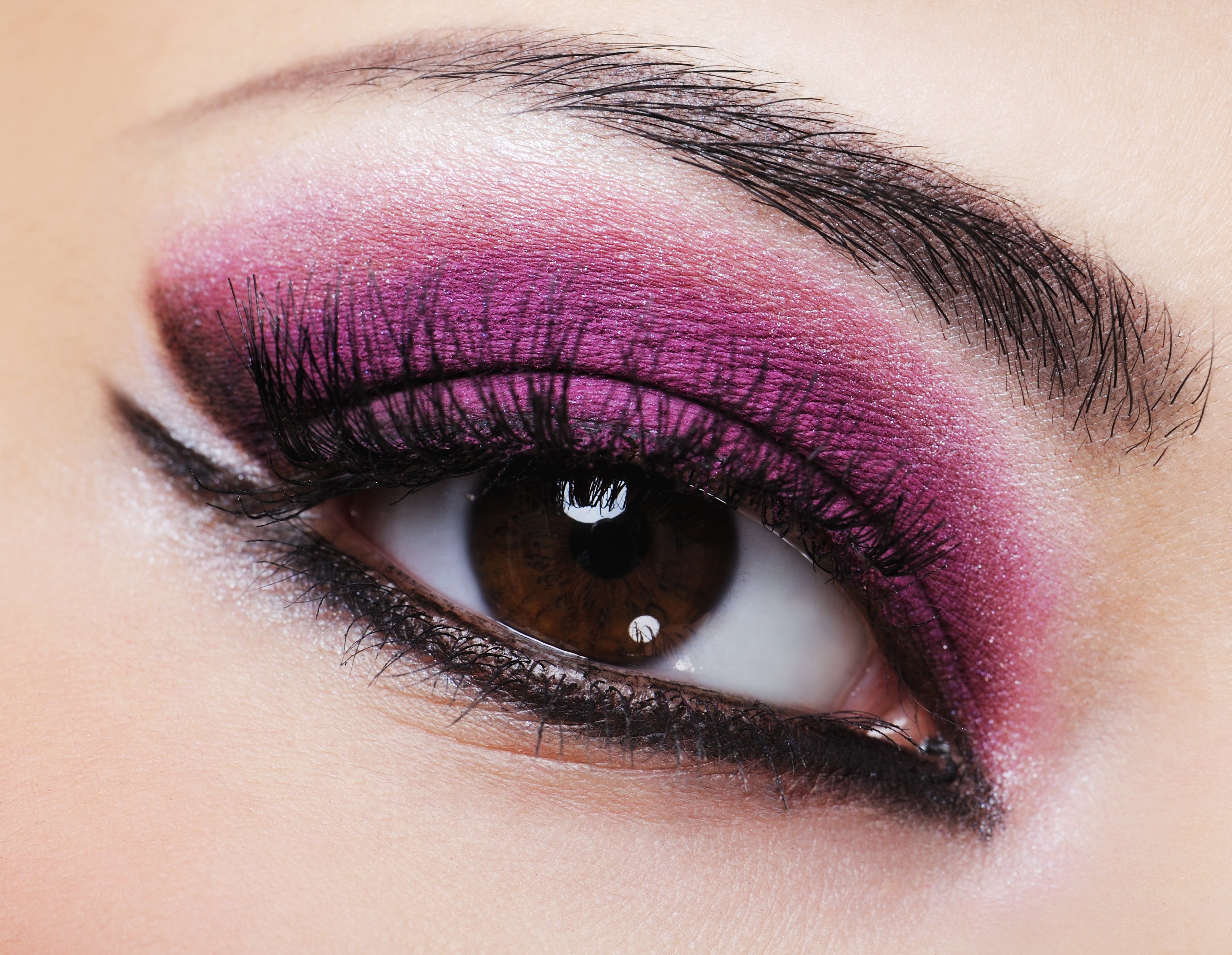 Ojo femenino color marrón con maquillaje violeta brillante. | Foto: Shutterstock