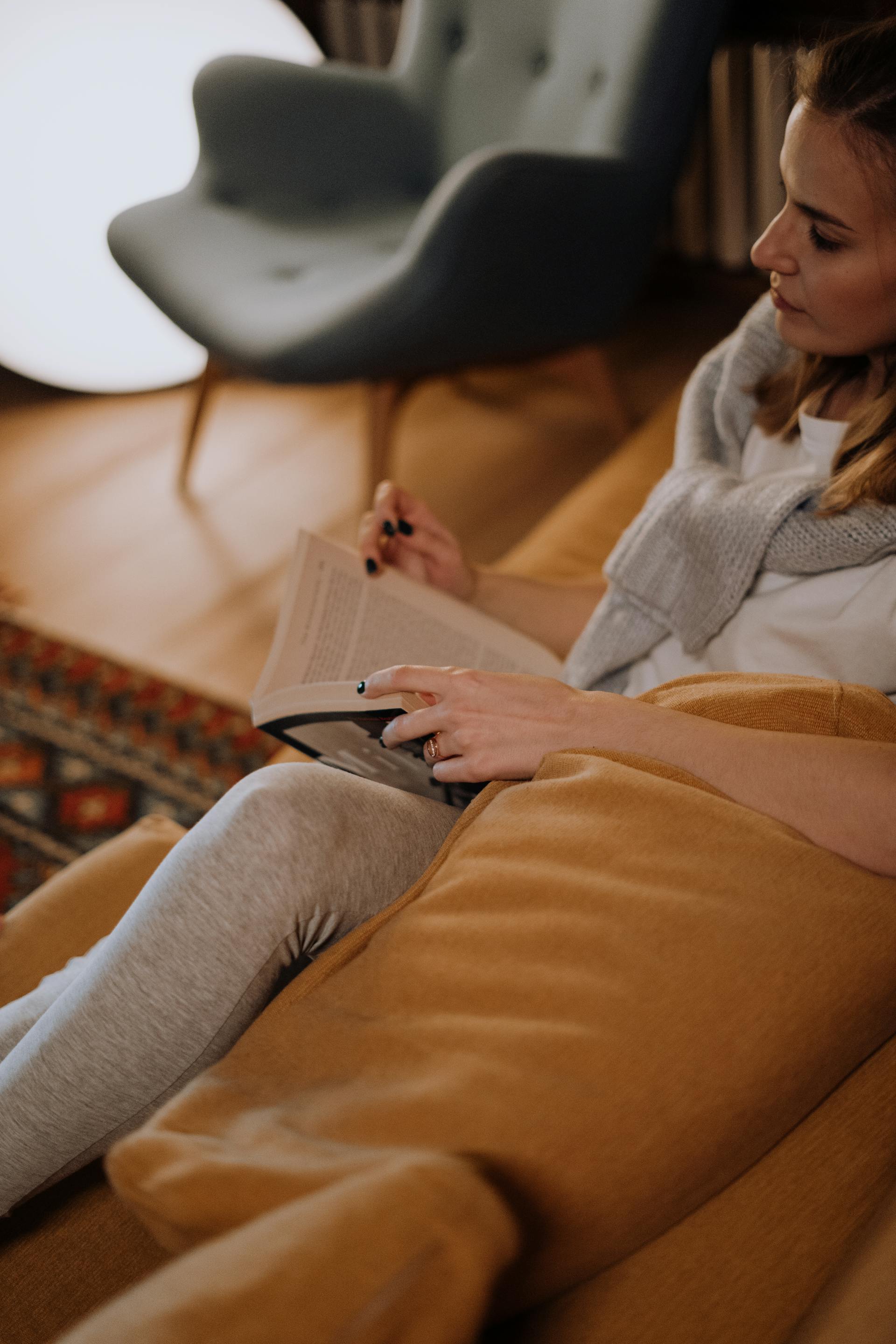 Una mujer con un libro en el sofá | Fuente: Pexels