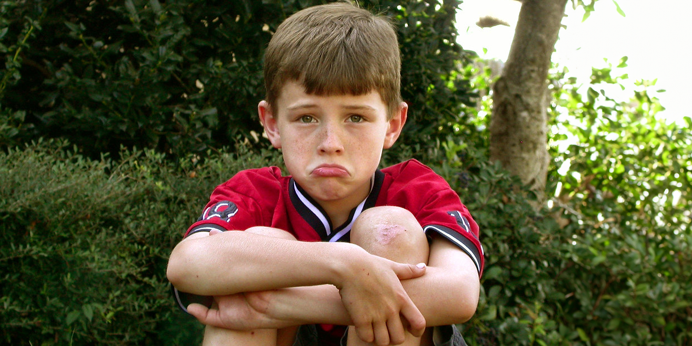 Niño triste sentado en el suelo | Fuente: Flickr