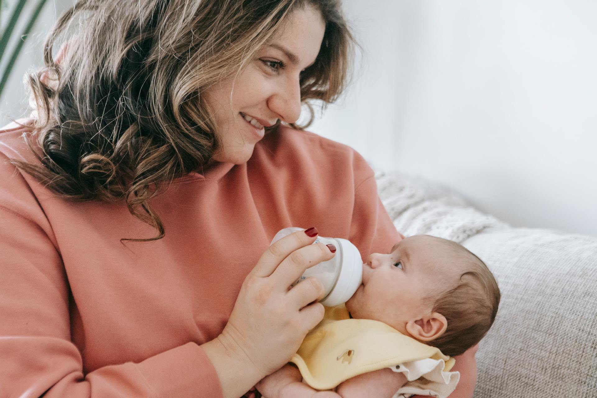 Una madre feliz alimentando a su bebé | Fuente: Pexels