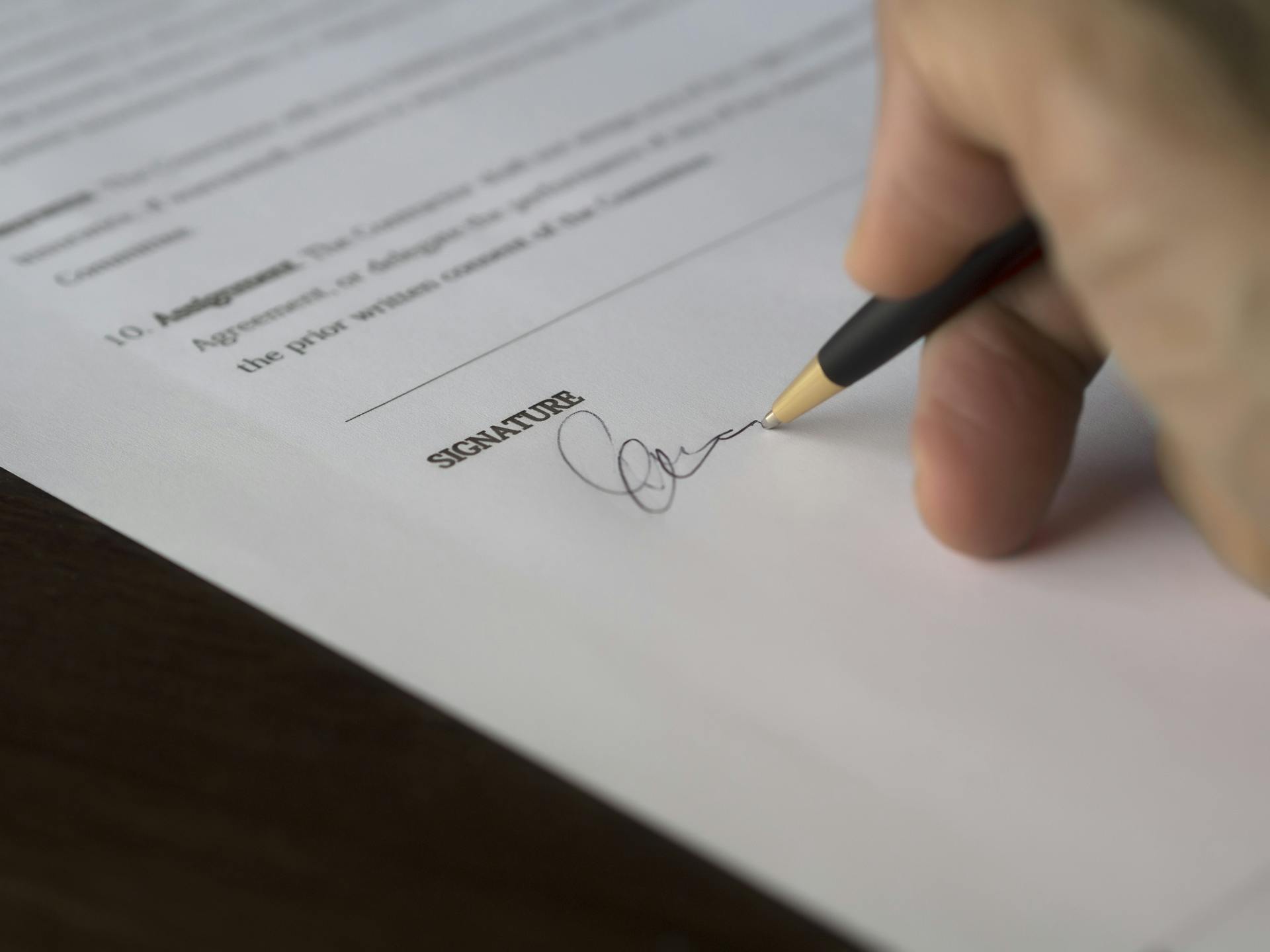 Una persona firmando un documento | Fuente: Pexels