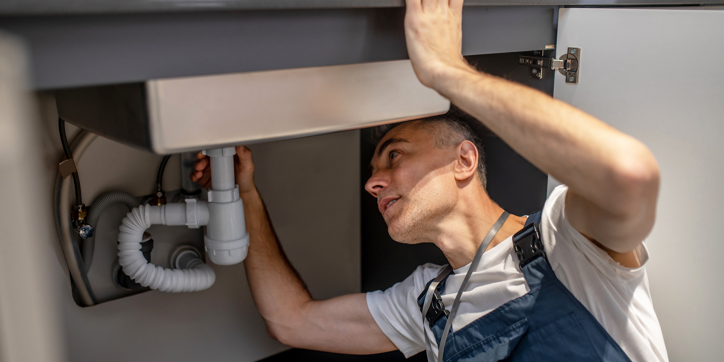Un hombre arreglando un fregadero de cocina | Fuente: Shutterstock