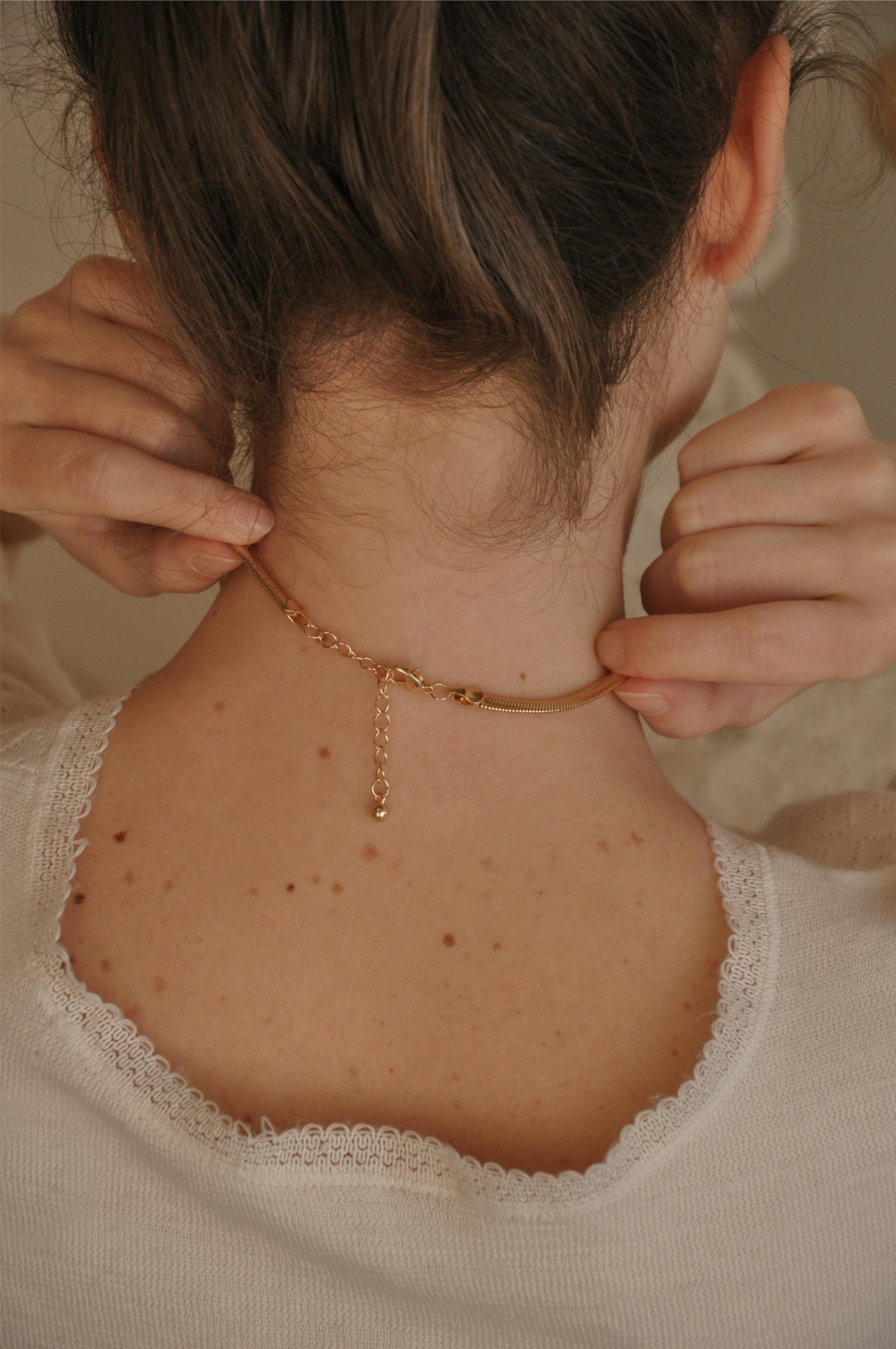 Vista trasera de una mujer tocándose el collar | Fuente: Pexels