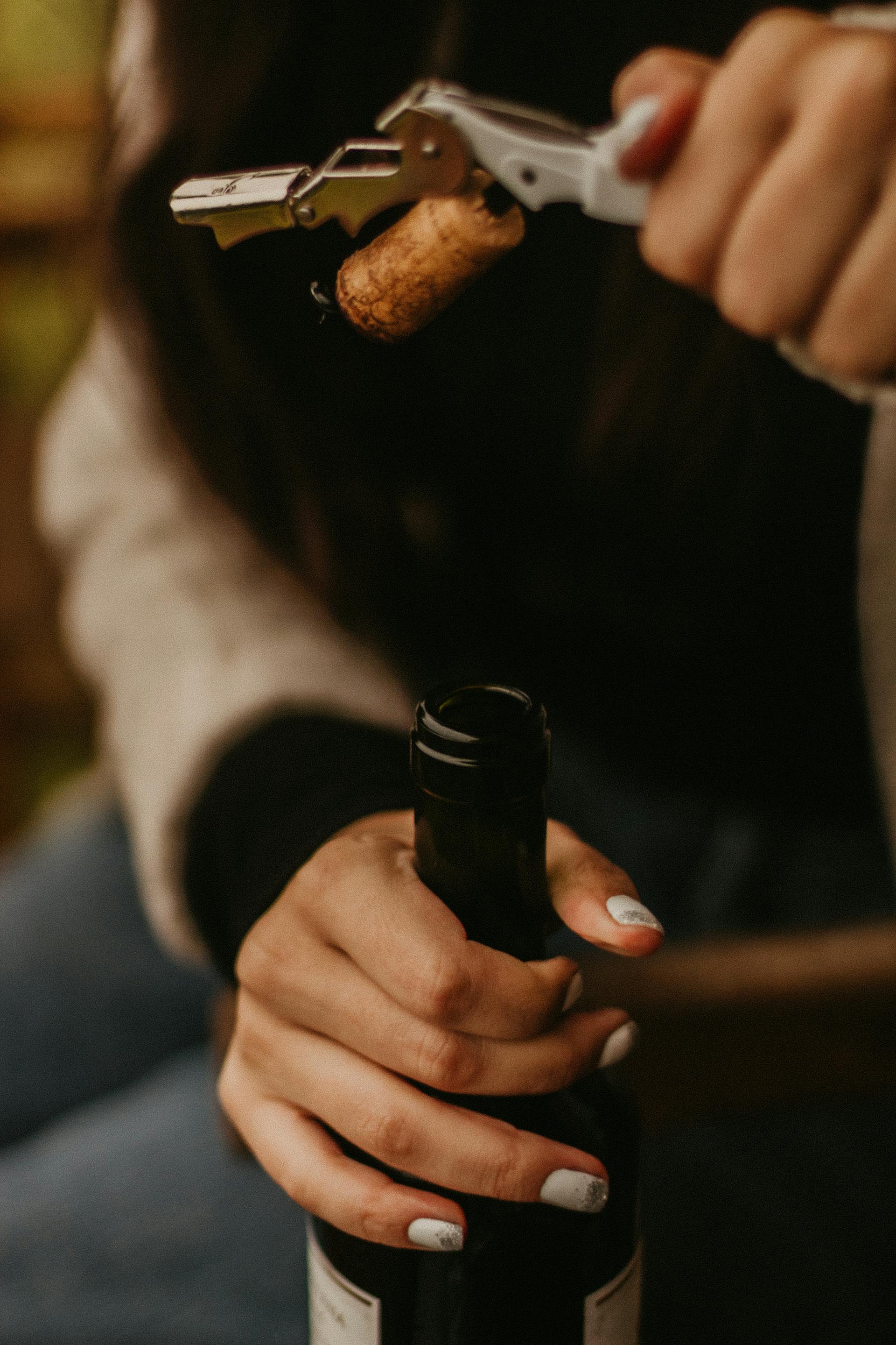 Una mujer abriendo una botella de vino | Fuente: Pexels