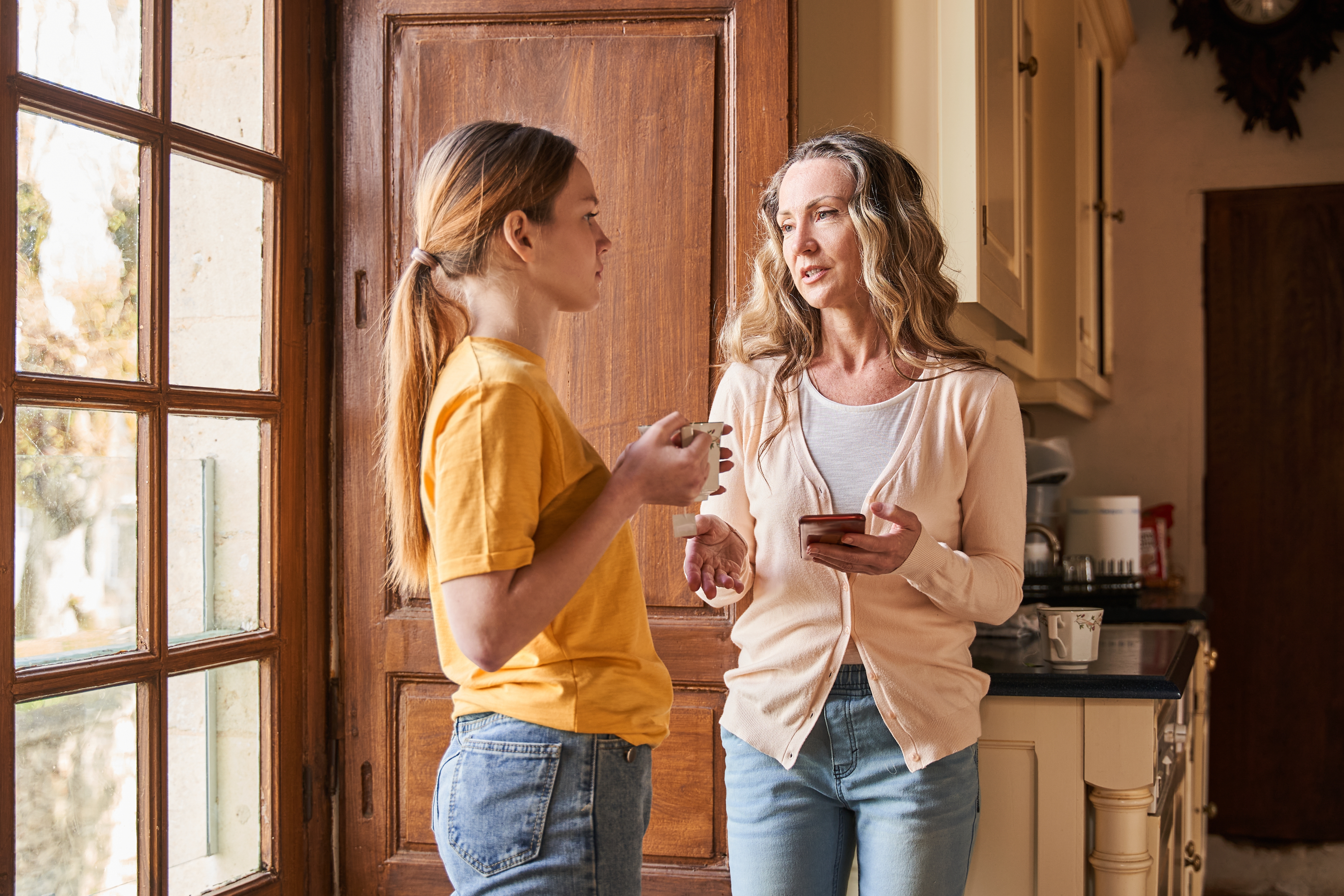 Una mujer habla con su hija cerca de la puerta | Fuente: Shutterstock