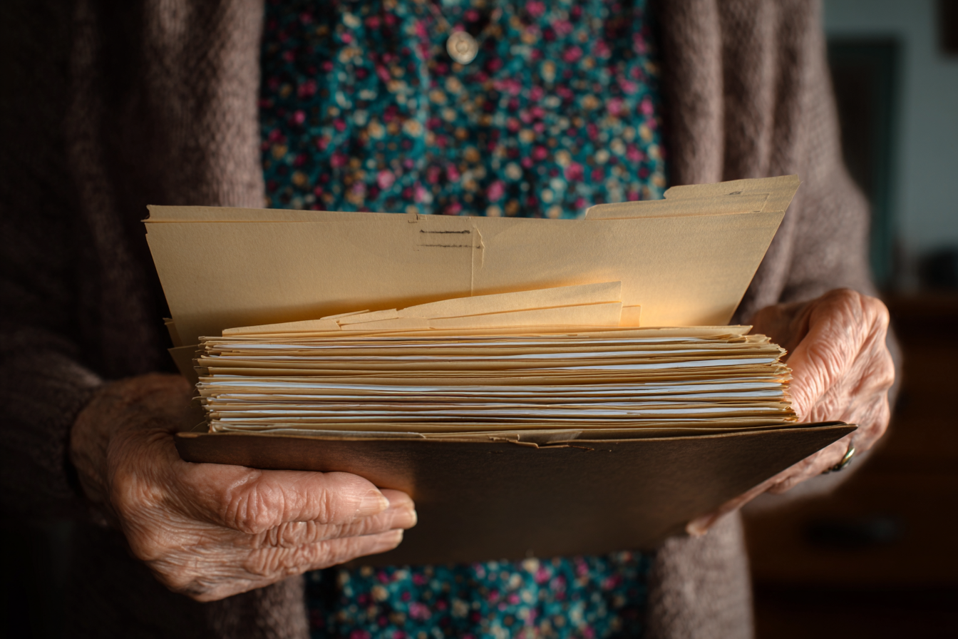 Una donna anziana con una cartella in mano | Fonte: Midjourney