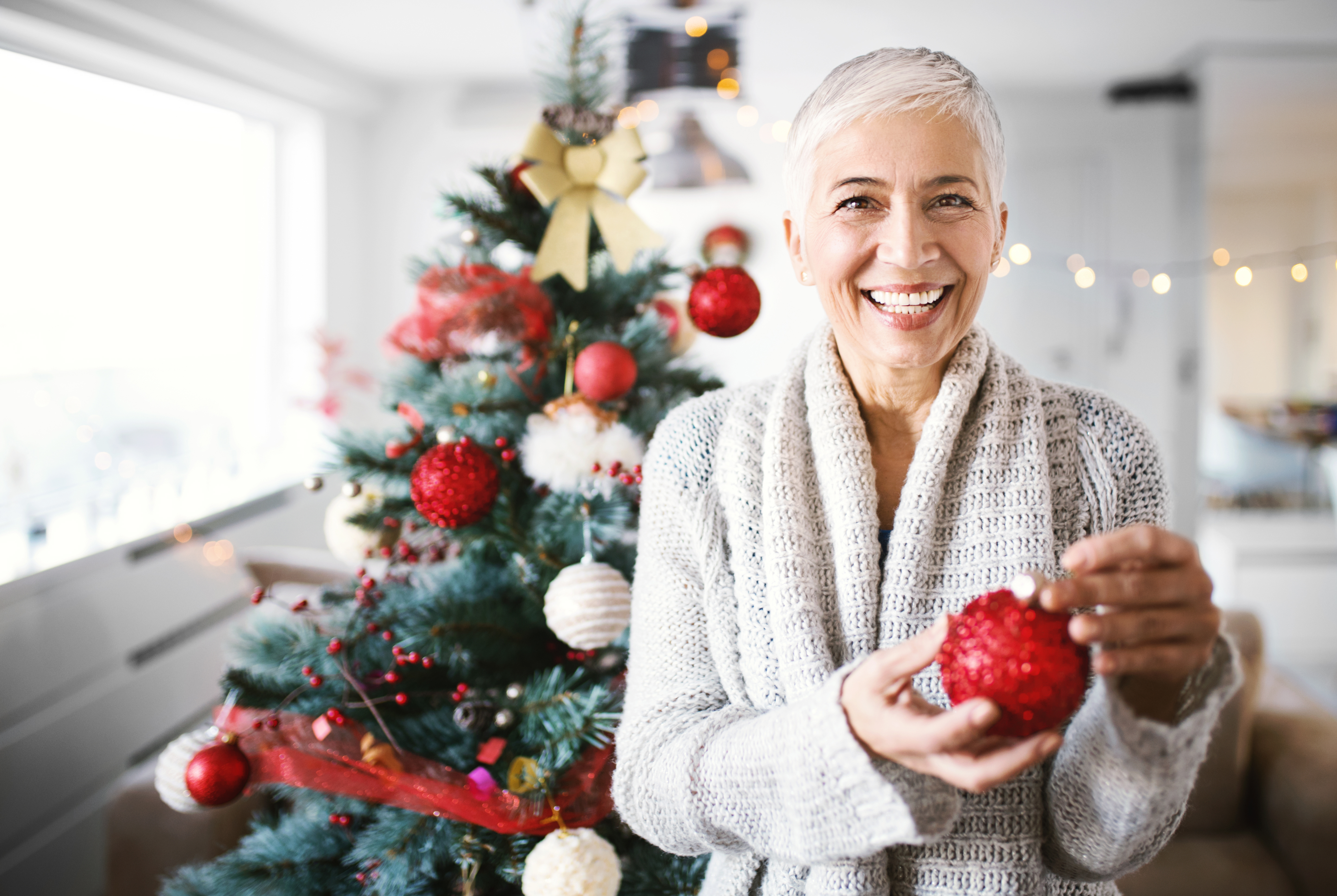 Una mujer mayor decorando su árbol de Navidad. | Foto: Getty Images