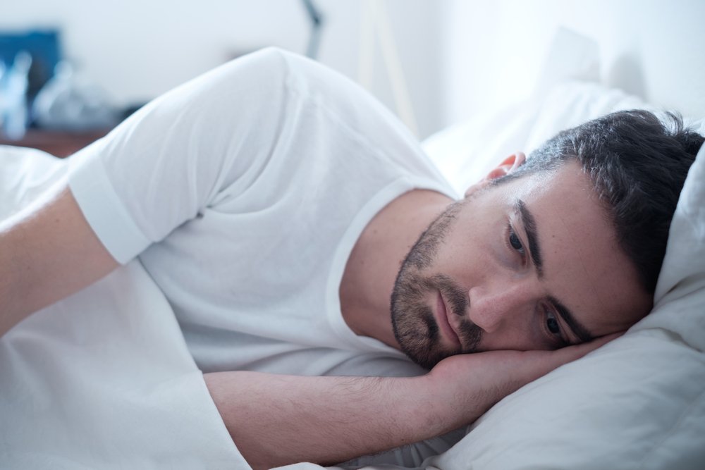 Hombre con rostro triste recostado de lado en una cama. | Foto: Shutterstock