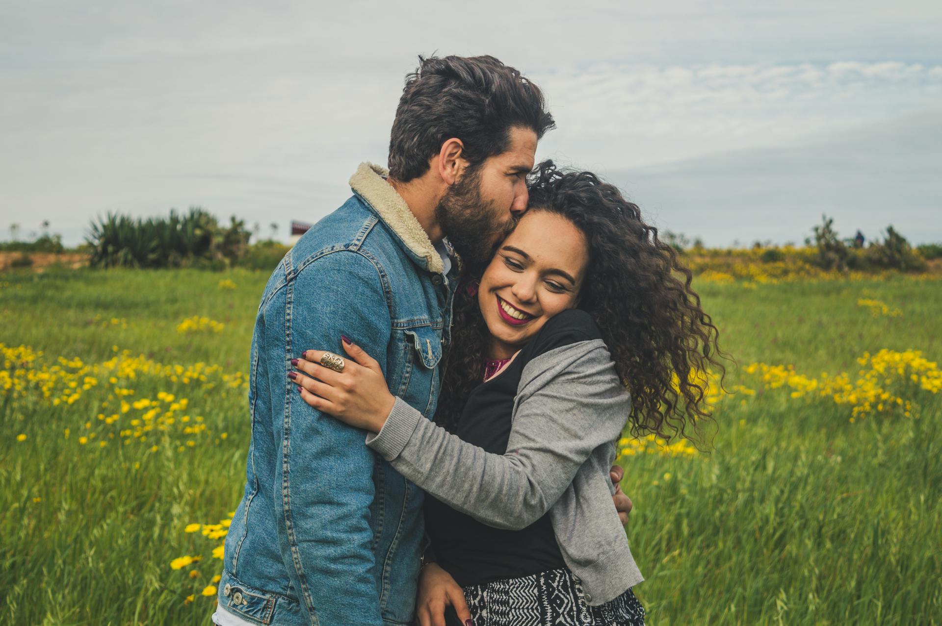 Una joven pareja sonriendo en un campo | Foto: Pexels
