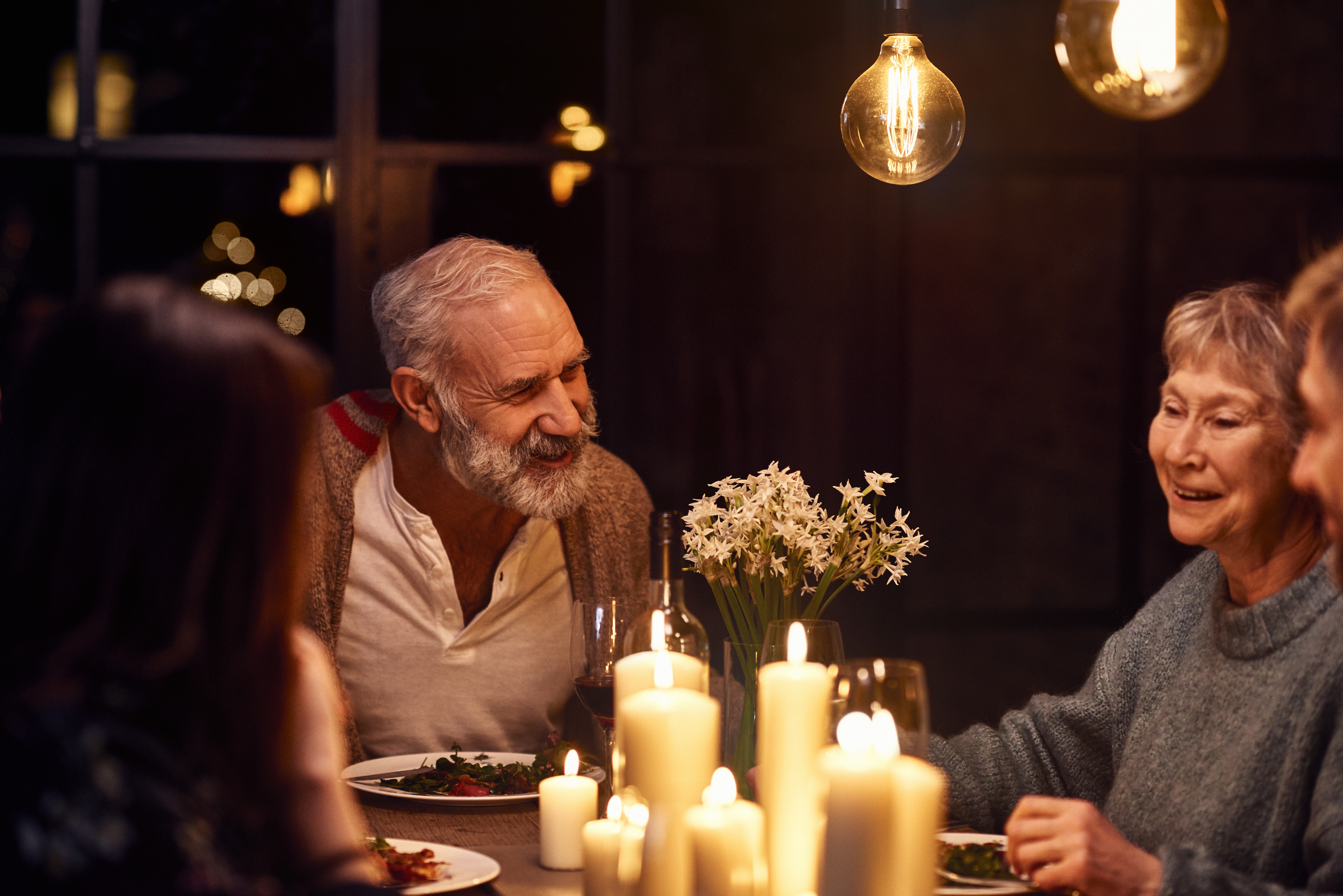 Hombre maduro hablando en una cena y sonriendo con su familia | Foto: Getty Images