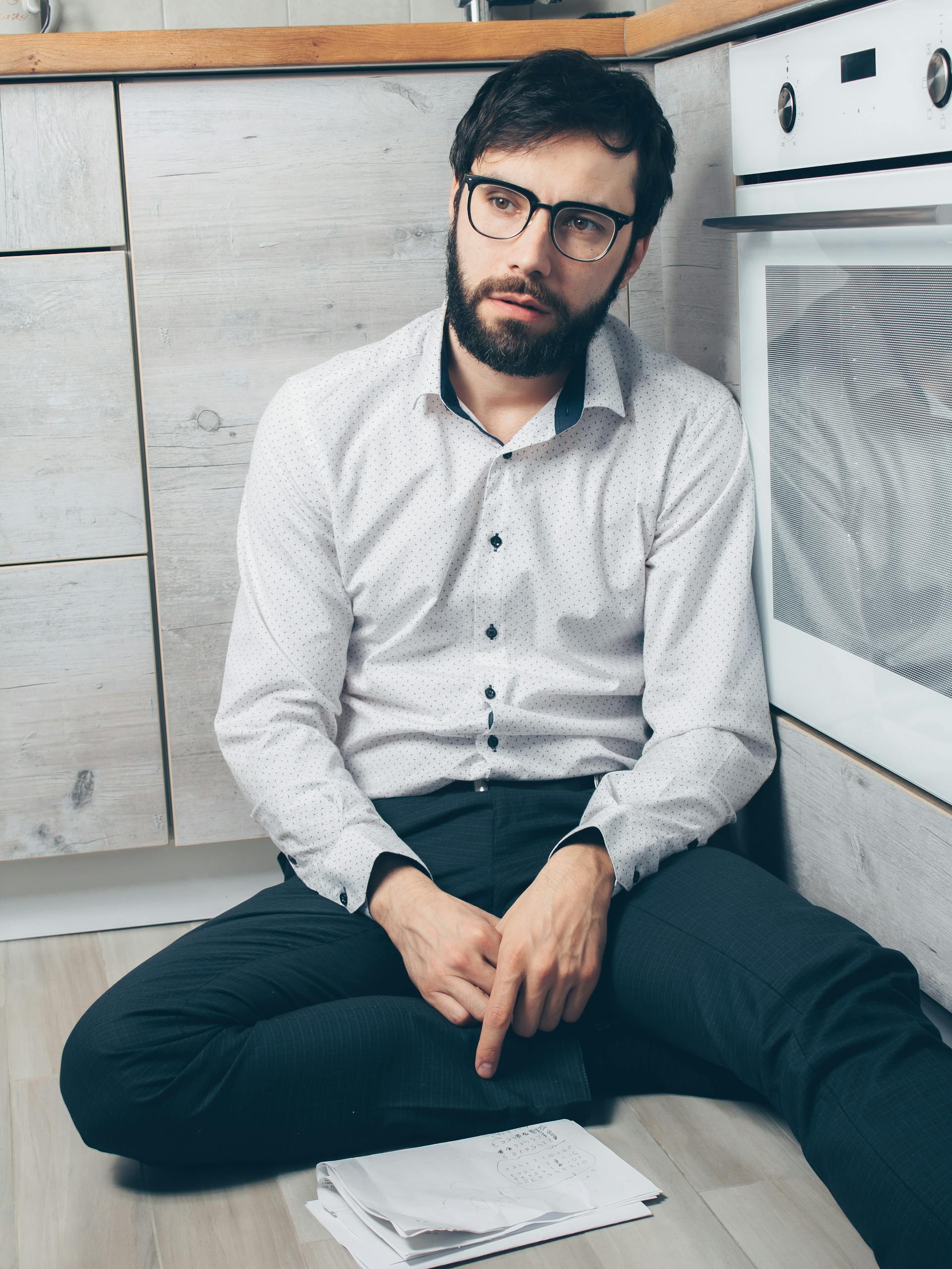 Un hombre conmocionado sentado en el suelo de una cocina | Fuente: Pexels