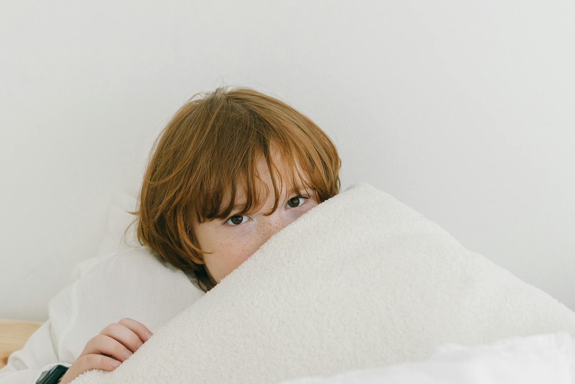 Un niño tumbado bajo su manta | Fuente: Pexels