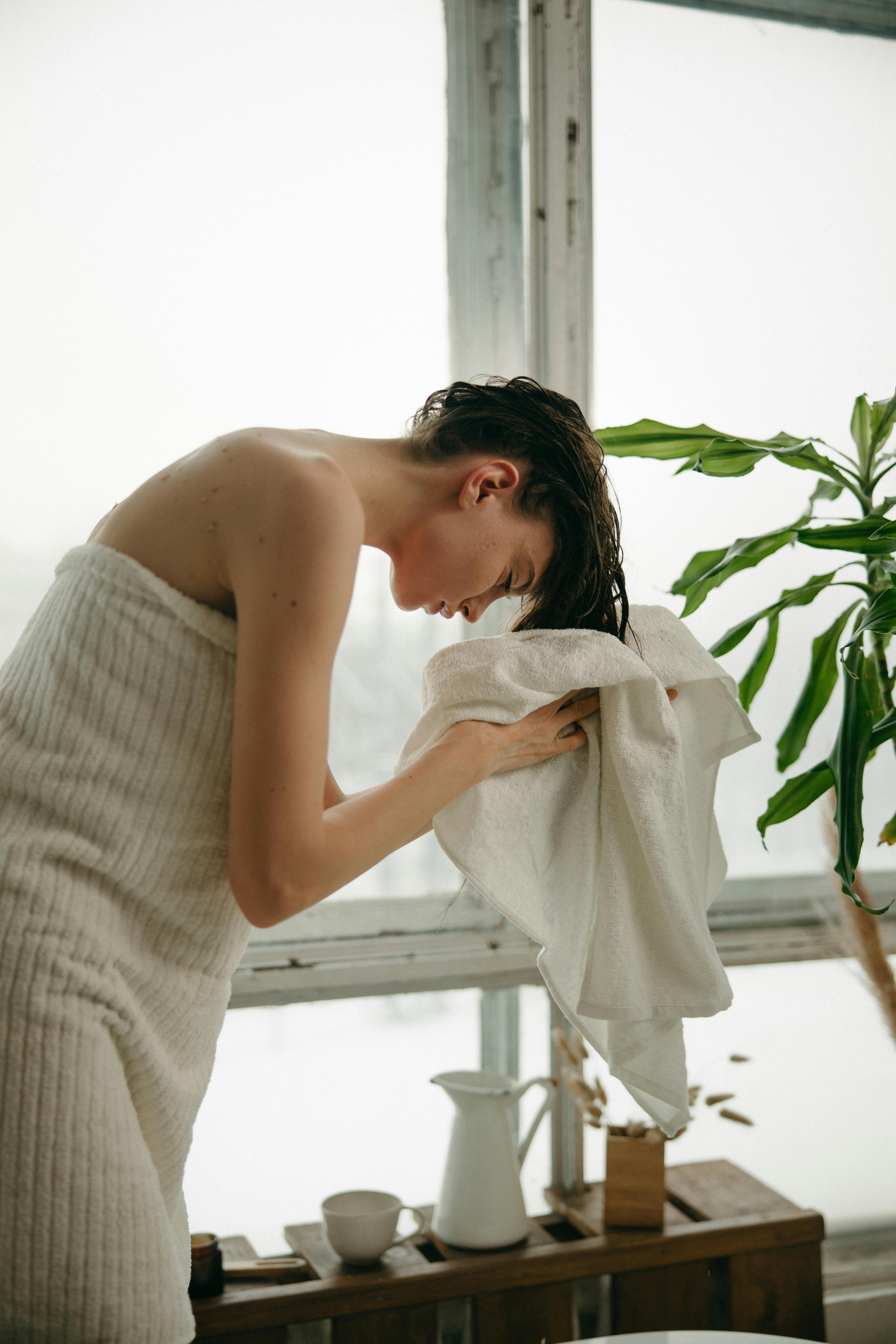 Una mujer secándose el pelo con una toalla después de ducharse | Fuente: Pexels