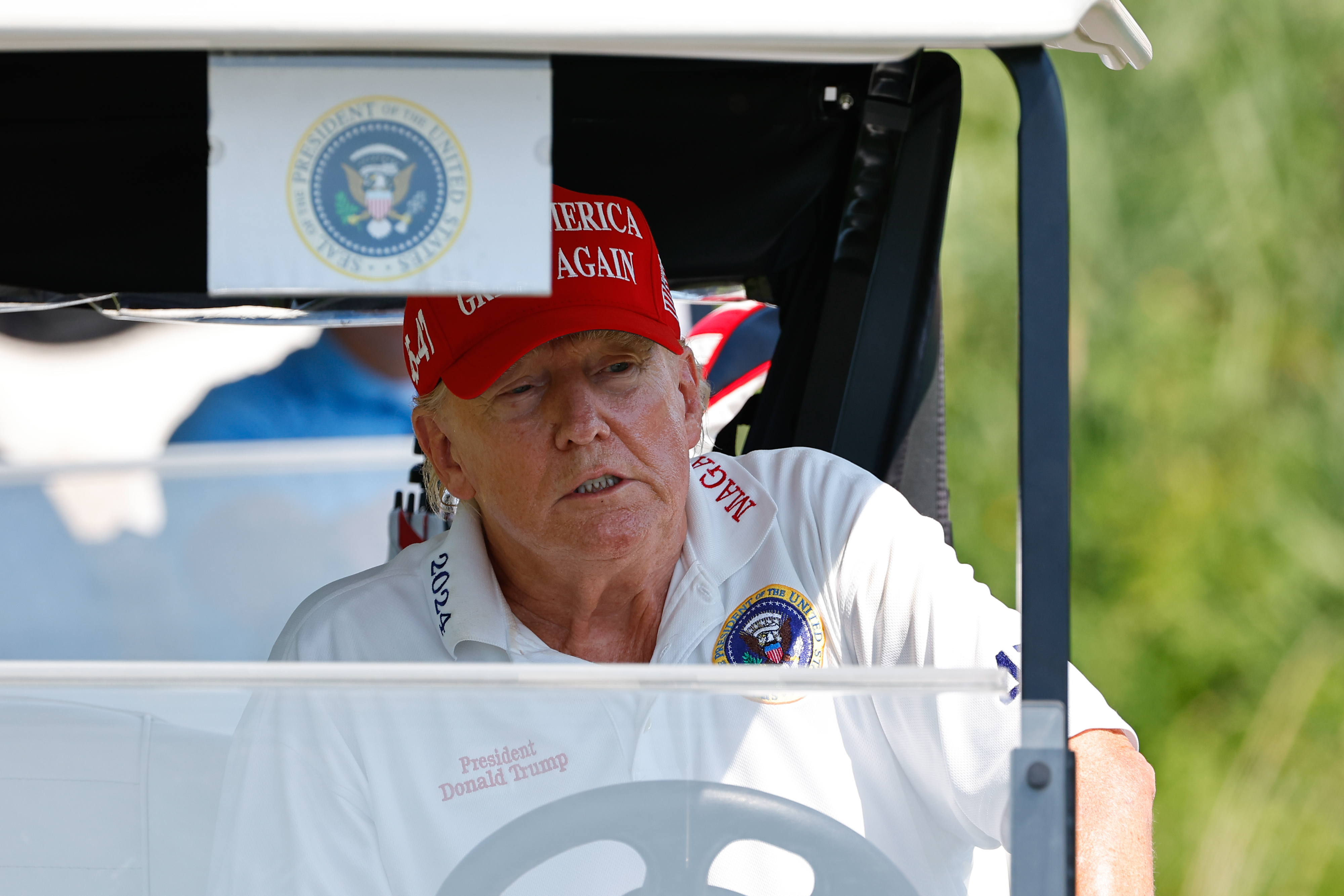 Se ve al presidente Donald Trump conduciendo un carrito de golf desde el tee del hoyo 15 durante la ronda de prácticas en el Trump National Golf Club el 9 de agosto de 2023, en Bedminster, Nueva Jersey | Fuente: Getty Images