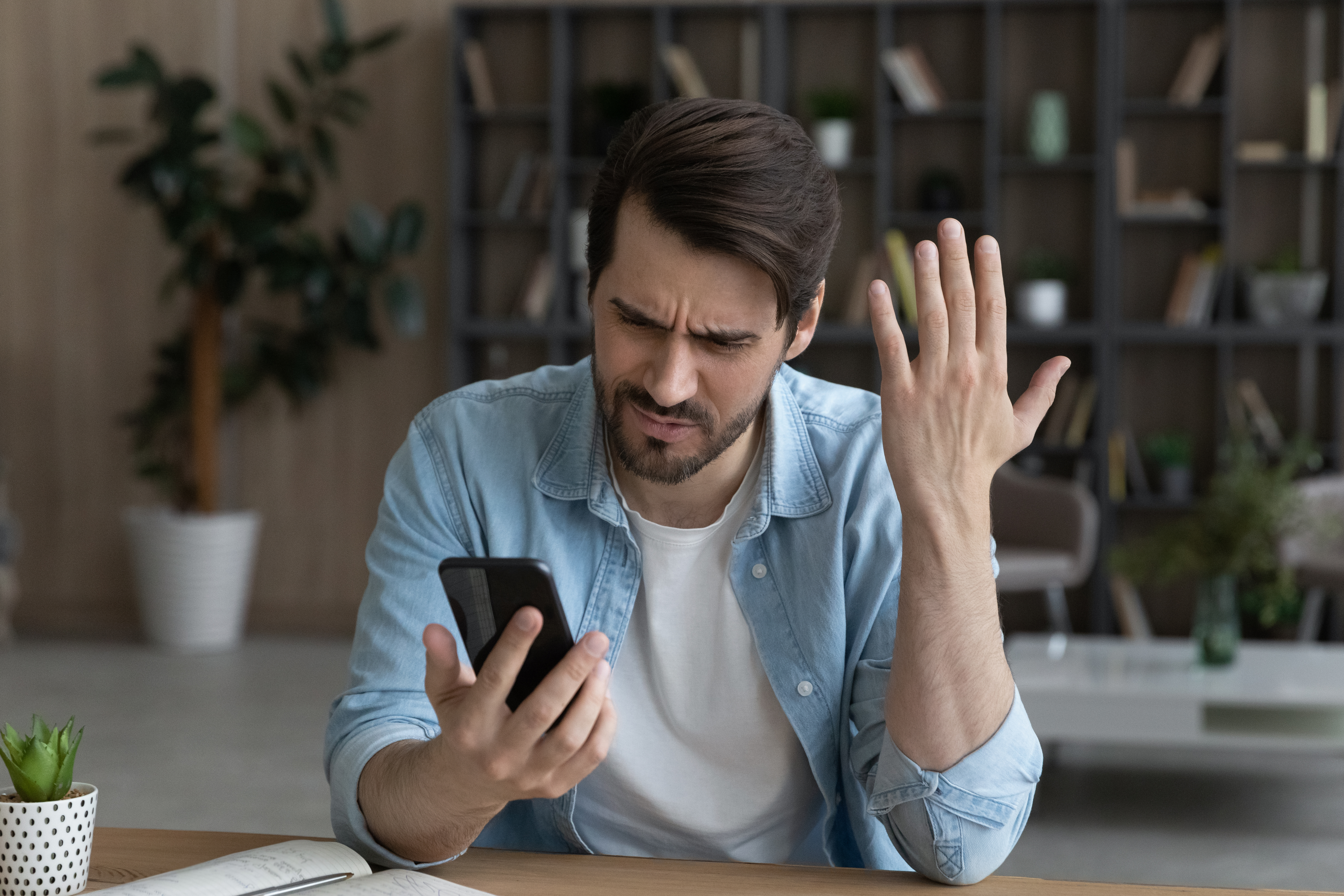 Un hombre frustrado y molesto con un teléfono en la mano | Fuente: Getty Images