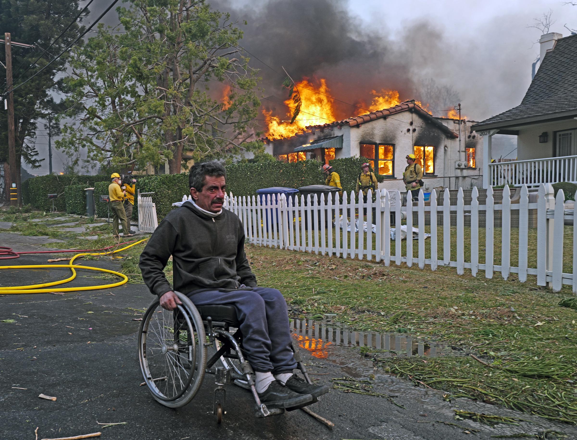 Un hombre en silla de ruedas pasa junto a una casa incendiada por el incendio de Eaton en el barrio de Altadena el 08 de enero de 2025, en Pasadena, California | Fuente: Getty Images