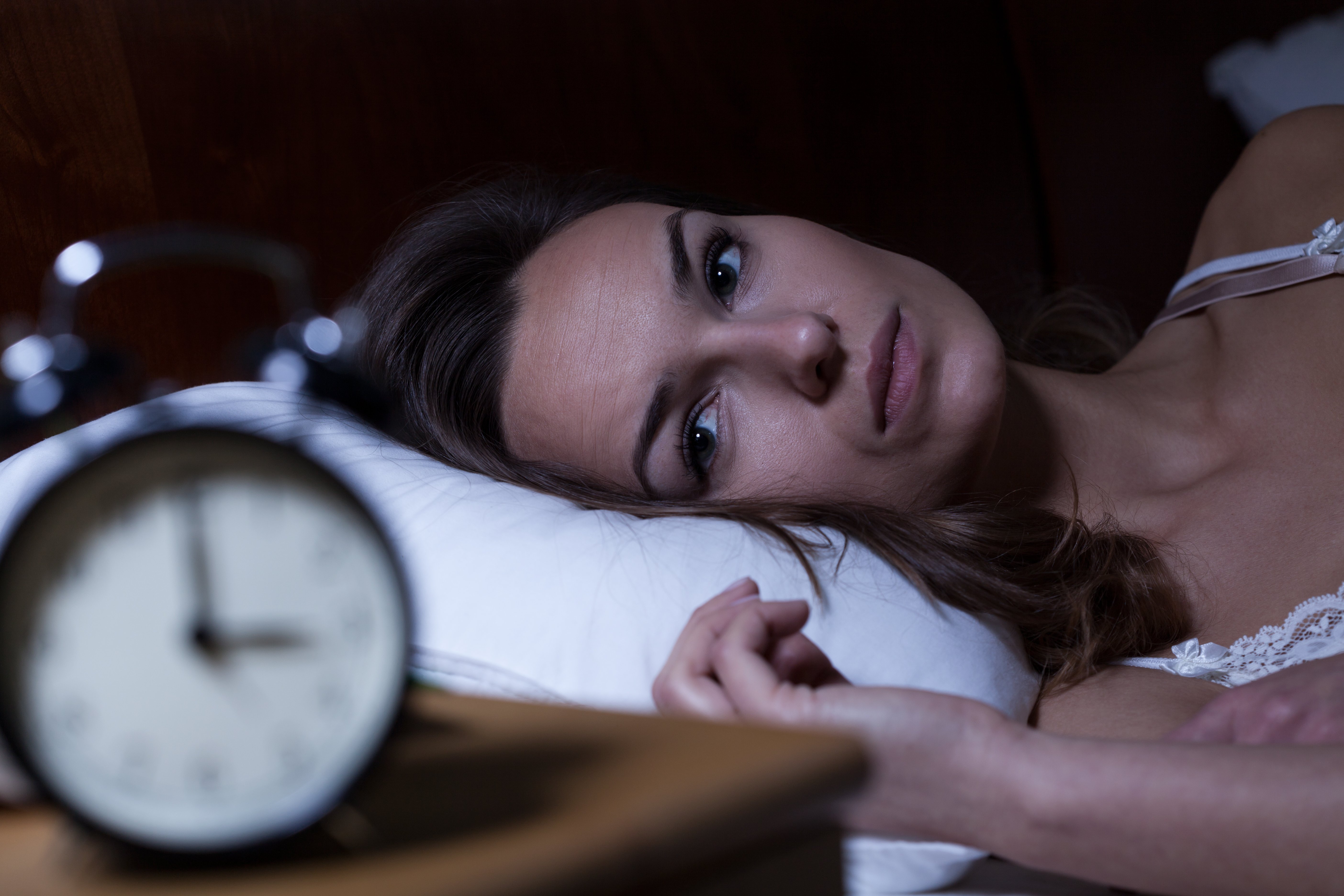 Mujer tendida en la cama sufriendo de insomnio. Fuente: Shutterstock