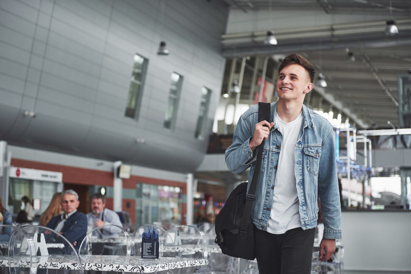 Un hombre sonriente caminando por un aeropuerto | Fuente: Freepik