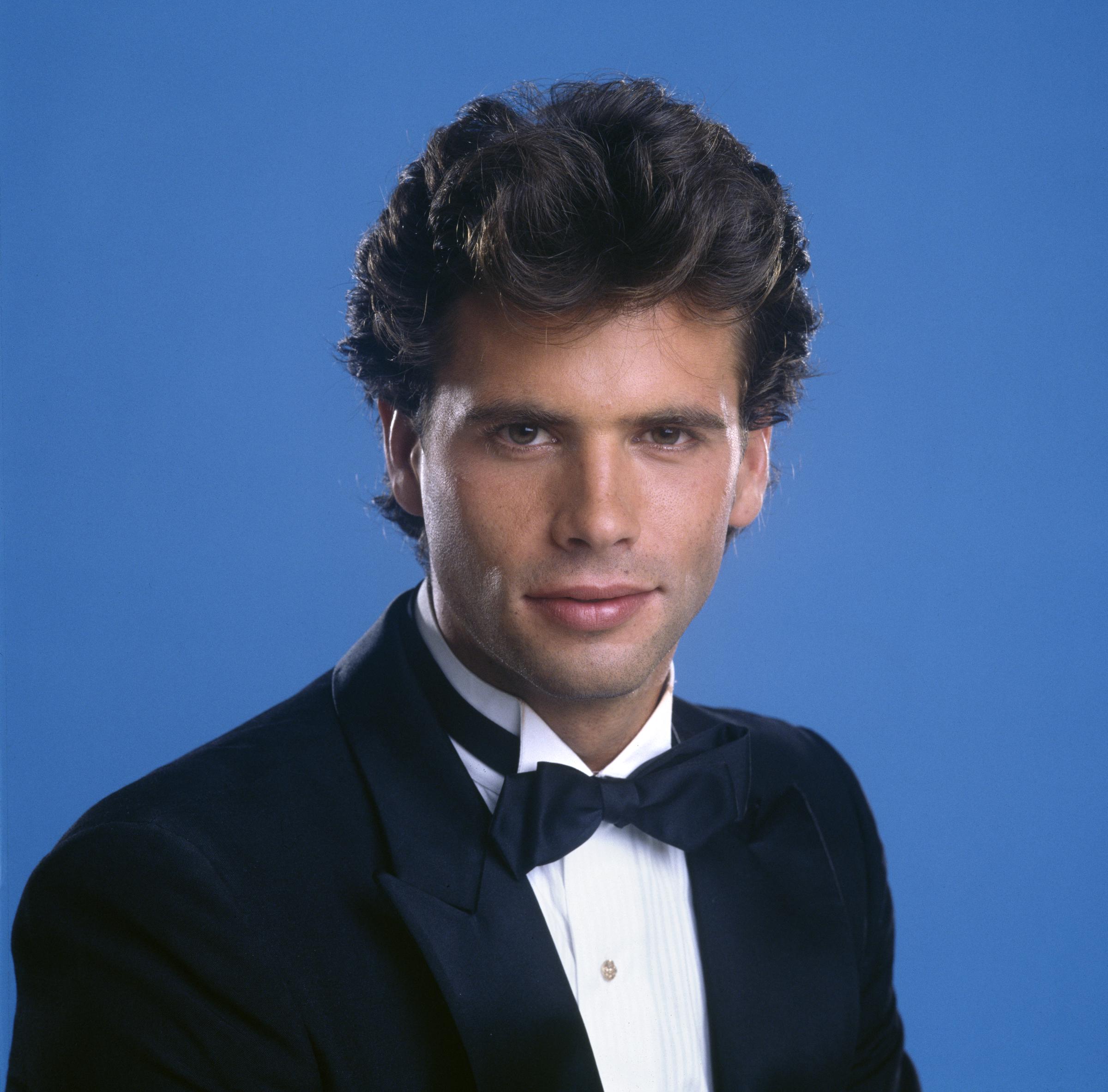 Lorenzo Lamas luce impecable durante la grabación de un segmento de CBS para "In Celebration 1886-1986: An American Portrait" el 1 de enero de 1985 en Los Ángeles, California. Ante un fondo azul intenso, el actor luce cabello oscuro ondulado y peinado, esmoquin negro clásico, camisa blanca plisada y moño negro. | Fuente: Getty Images