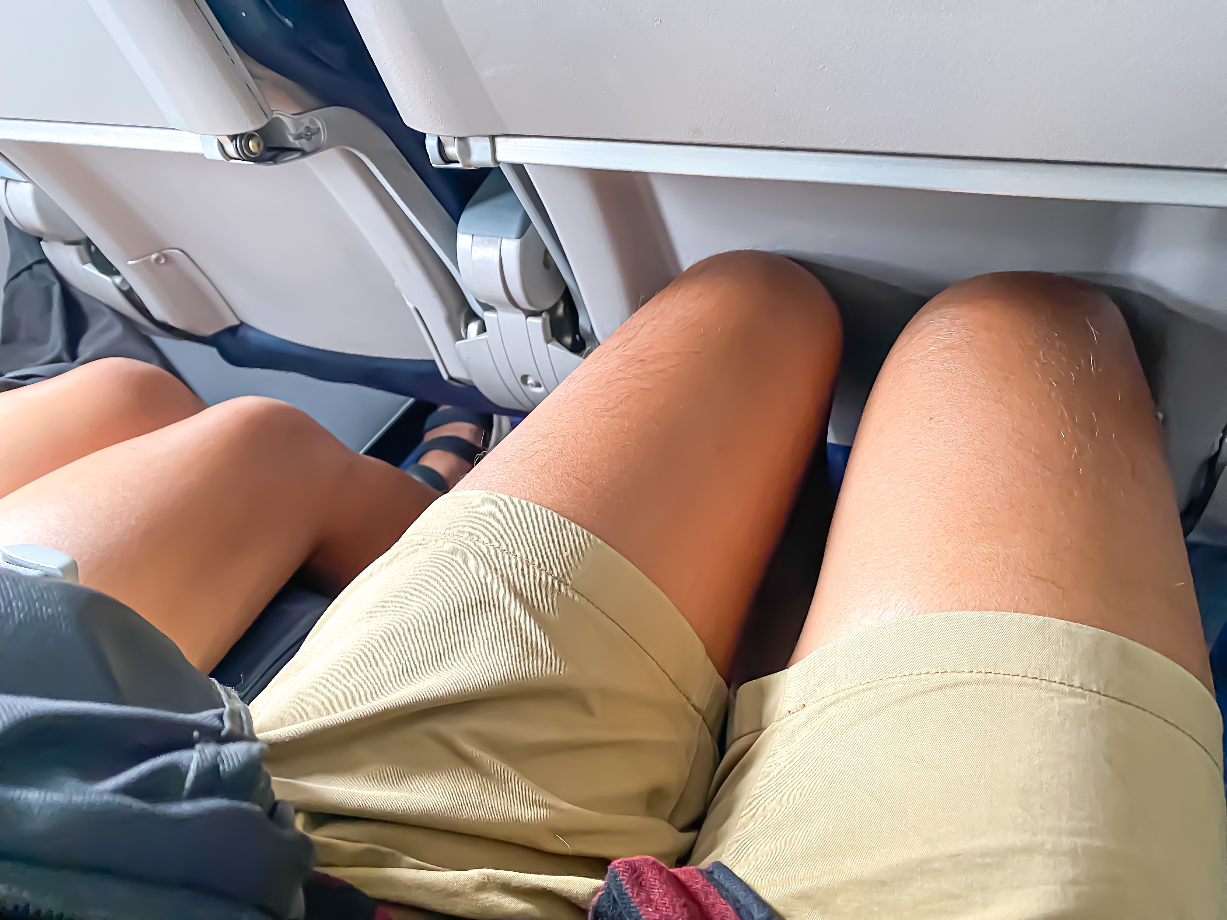 Piernas de personas sentadas en un avión | Fuente: Shutterstock