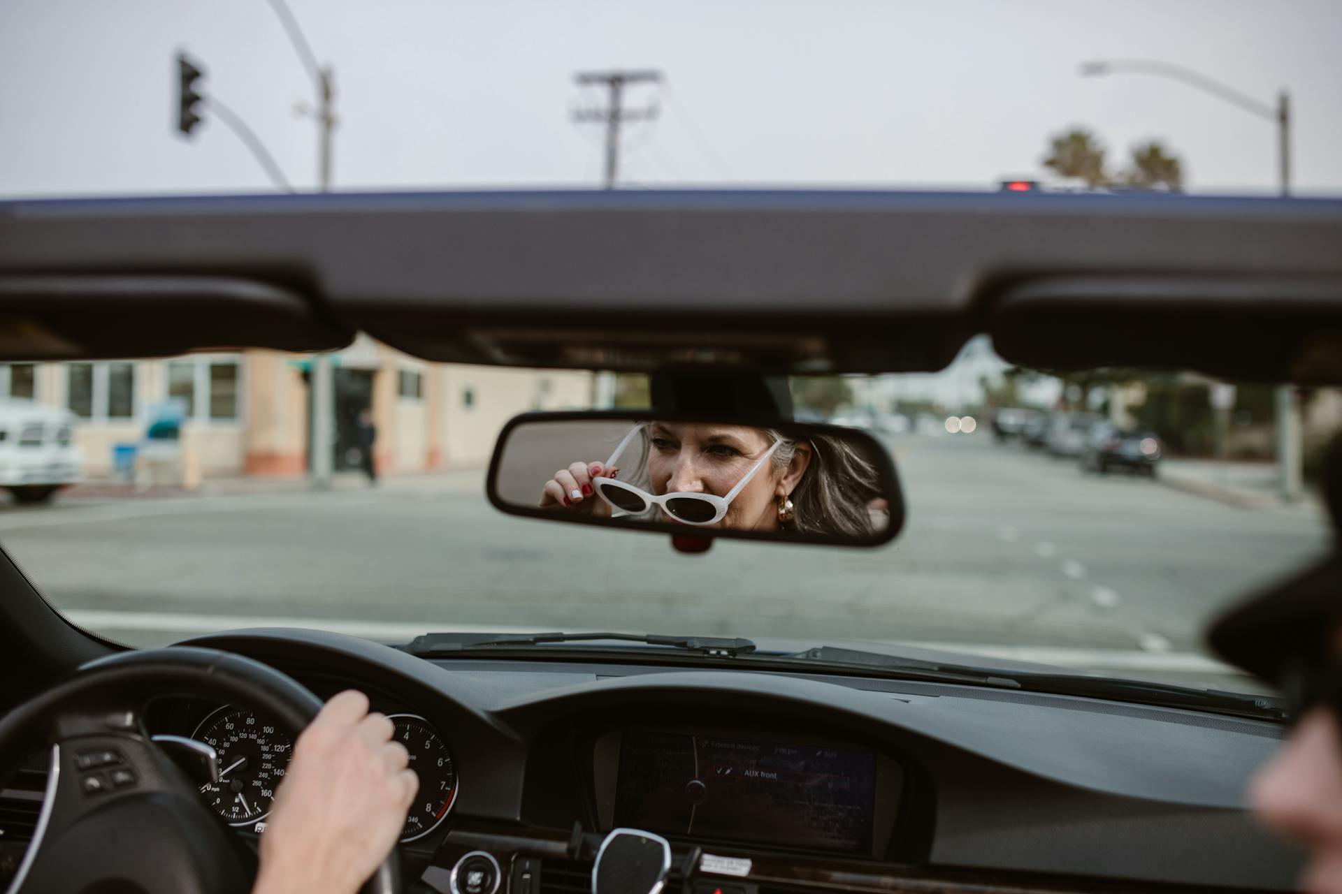 Reflejo de una mujer de mediana edad en el retrovisor conduciendo un Automóvil | Fuente: Pexels