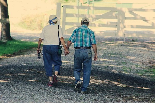 Pareja de abuelos camina tomada de la mano. | Pexels