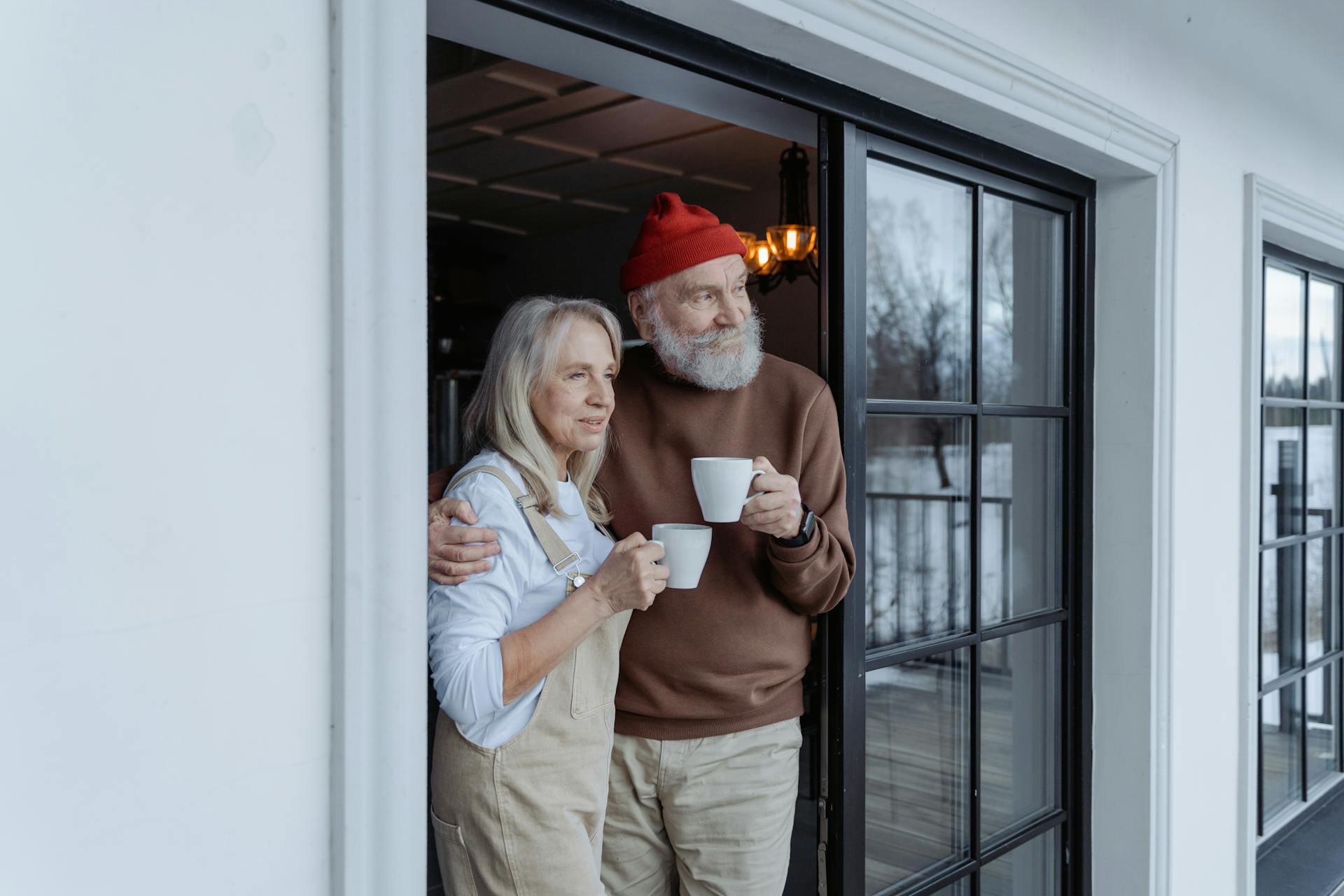 Una pareja de ancianos en el umbral de una puerta, cada uno con una taza en la mano | Fuente: Pexels