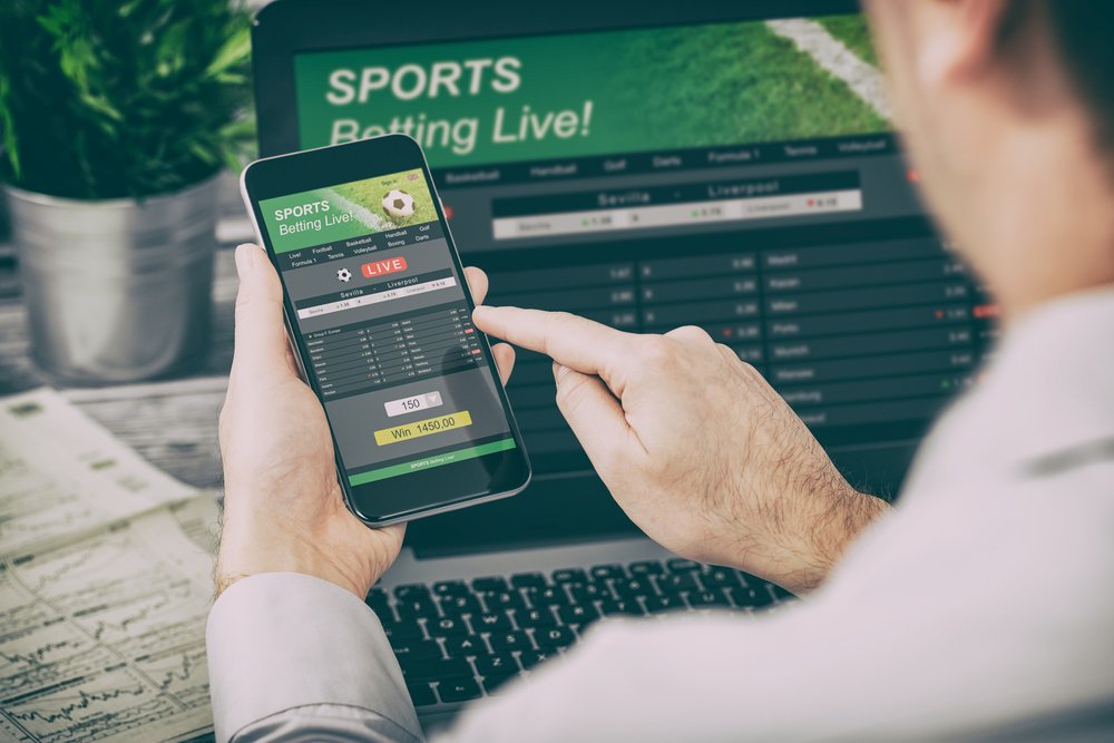 apostar apuestas deporte teléfono juego portátil sobre el hombro fútbol en directo concepto de sitio web en vivo. I Foto: Shutterstock
