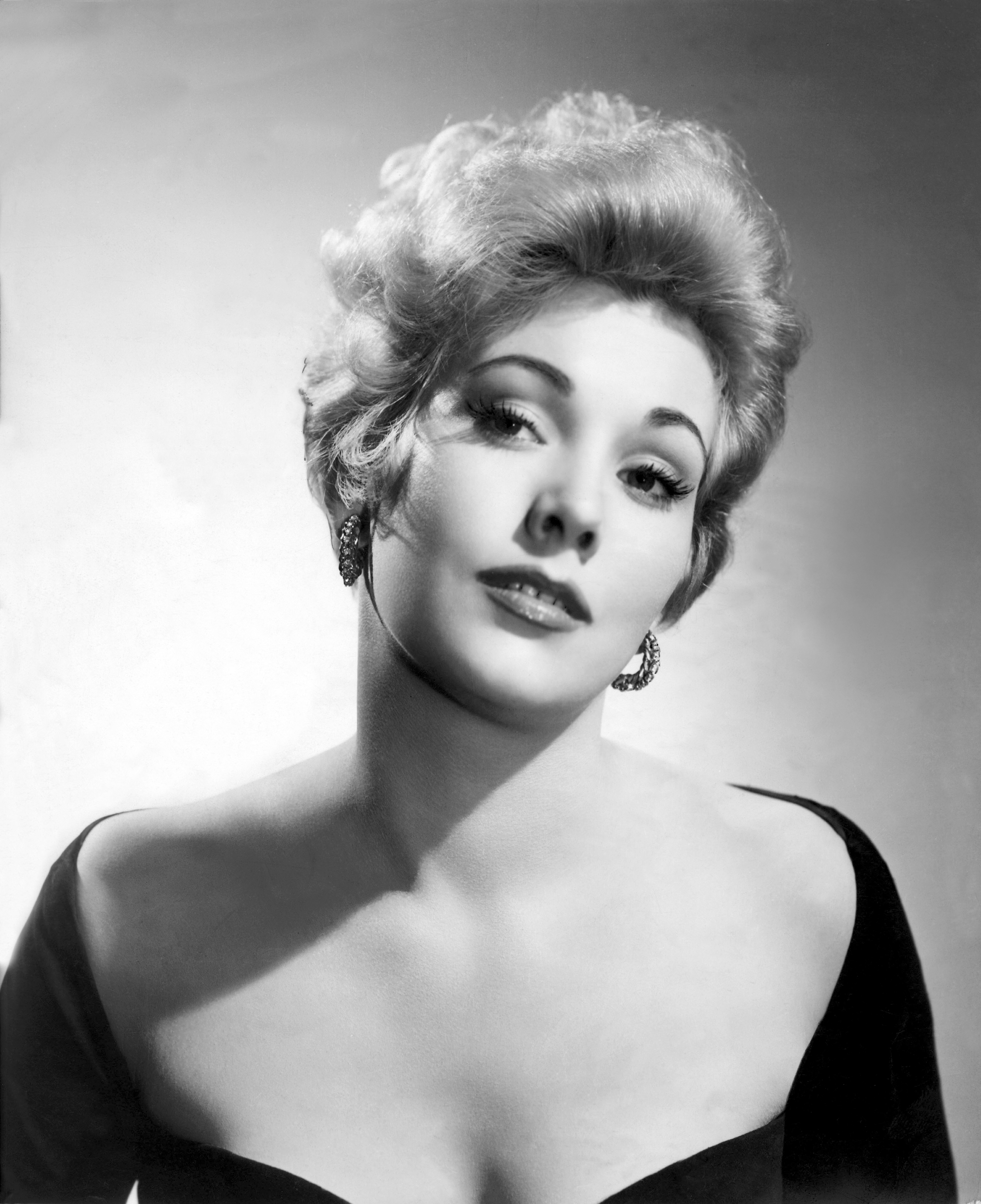 Kim Novak aparece en el plató de «Pushover», con un vestido claro y unos zapatos de tacón verdes, mientras posa en un sofá. | Fuente: Getty Images