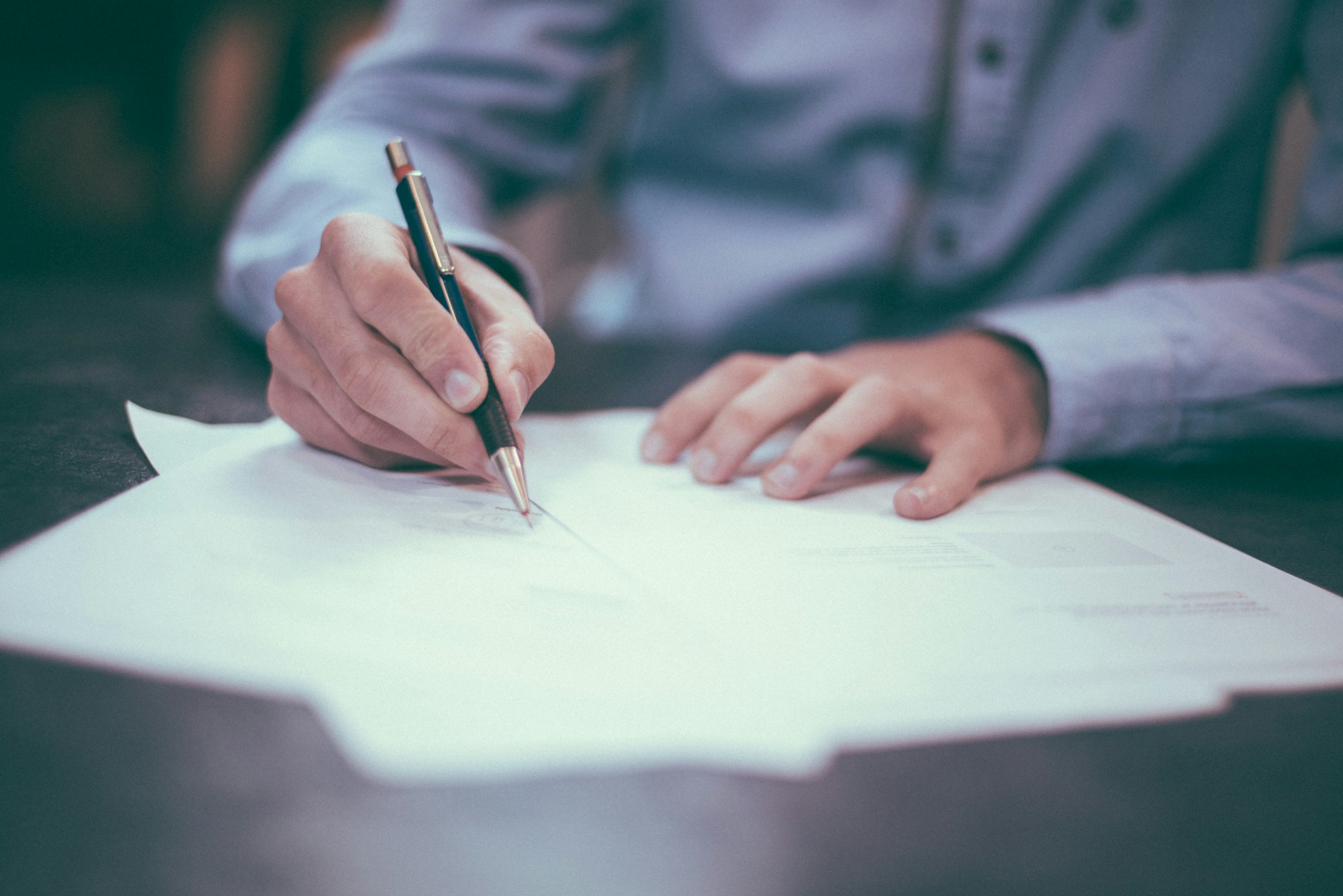 Una persona firmando un documento | Fuente: Unsplash