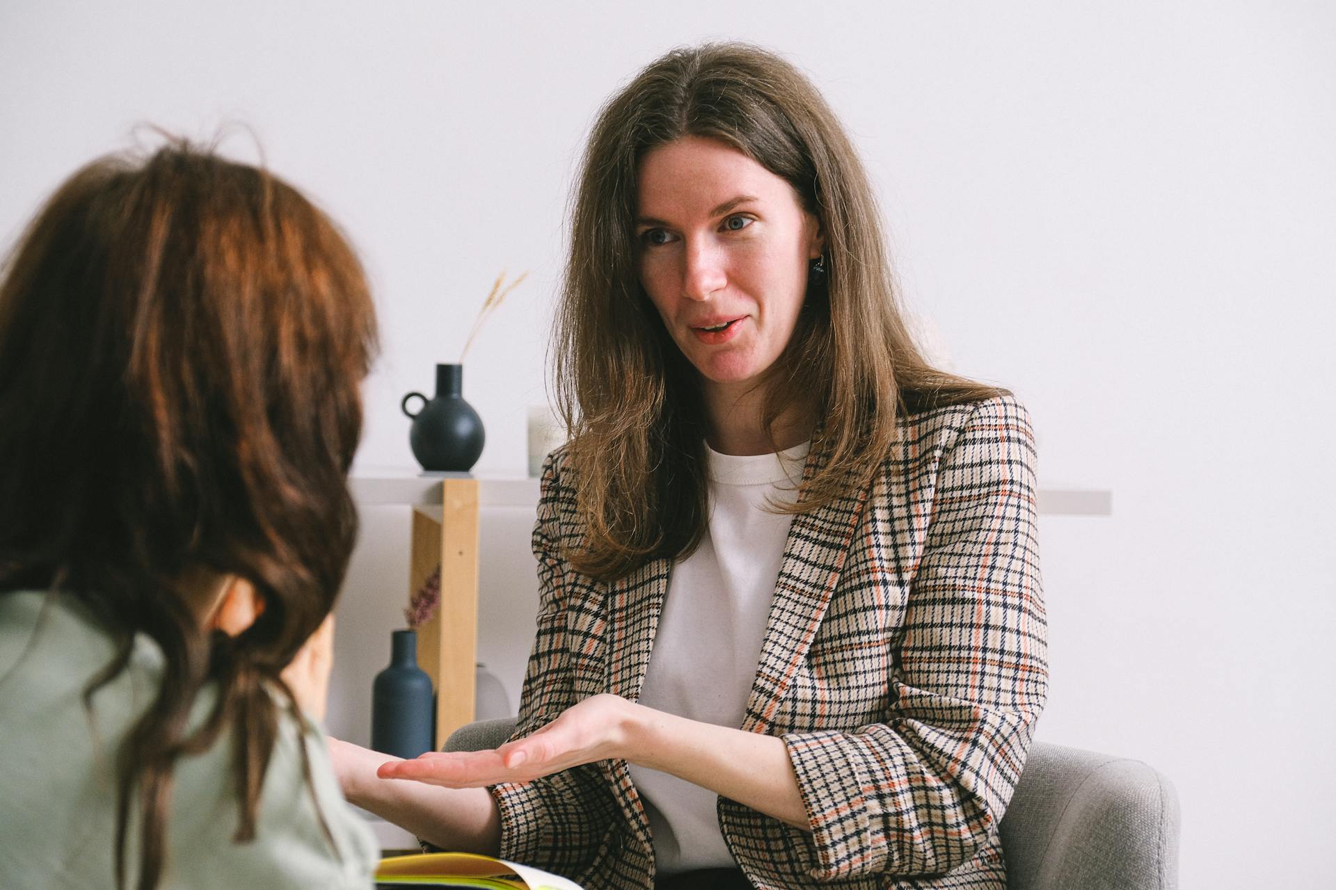 Una terapeuta sonriente hablando con una paciente en su consulta | Fuente: Pexels