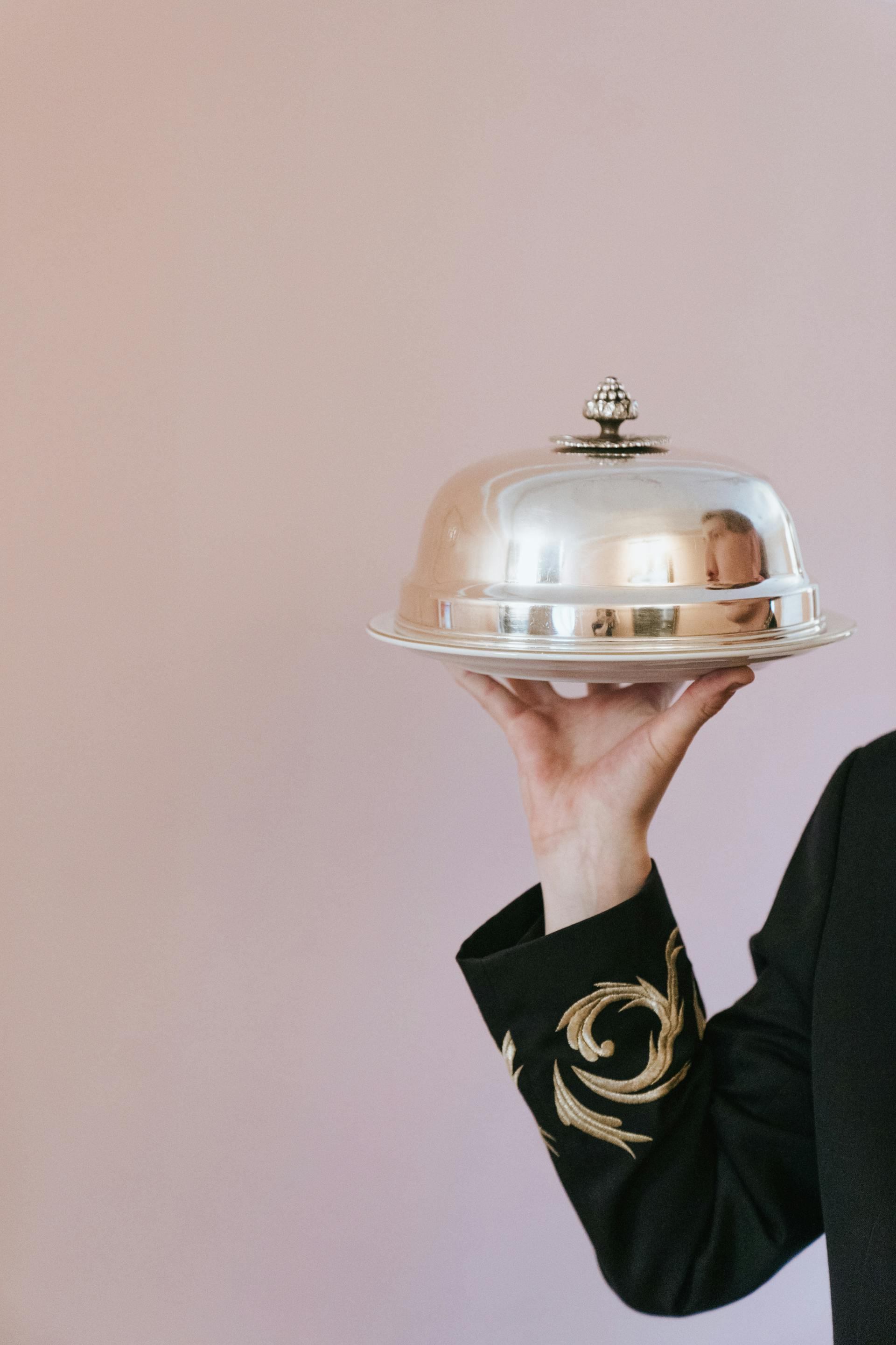 Una persona sostiene un plato cubierto por un cloche | Fuente: Pexels