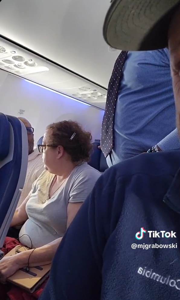 La pasajera sentada junto al alterado hombre reacciona mientras seguía gritando al personal de la aerolínea | Foto: TikTok/mjgrabowski